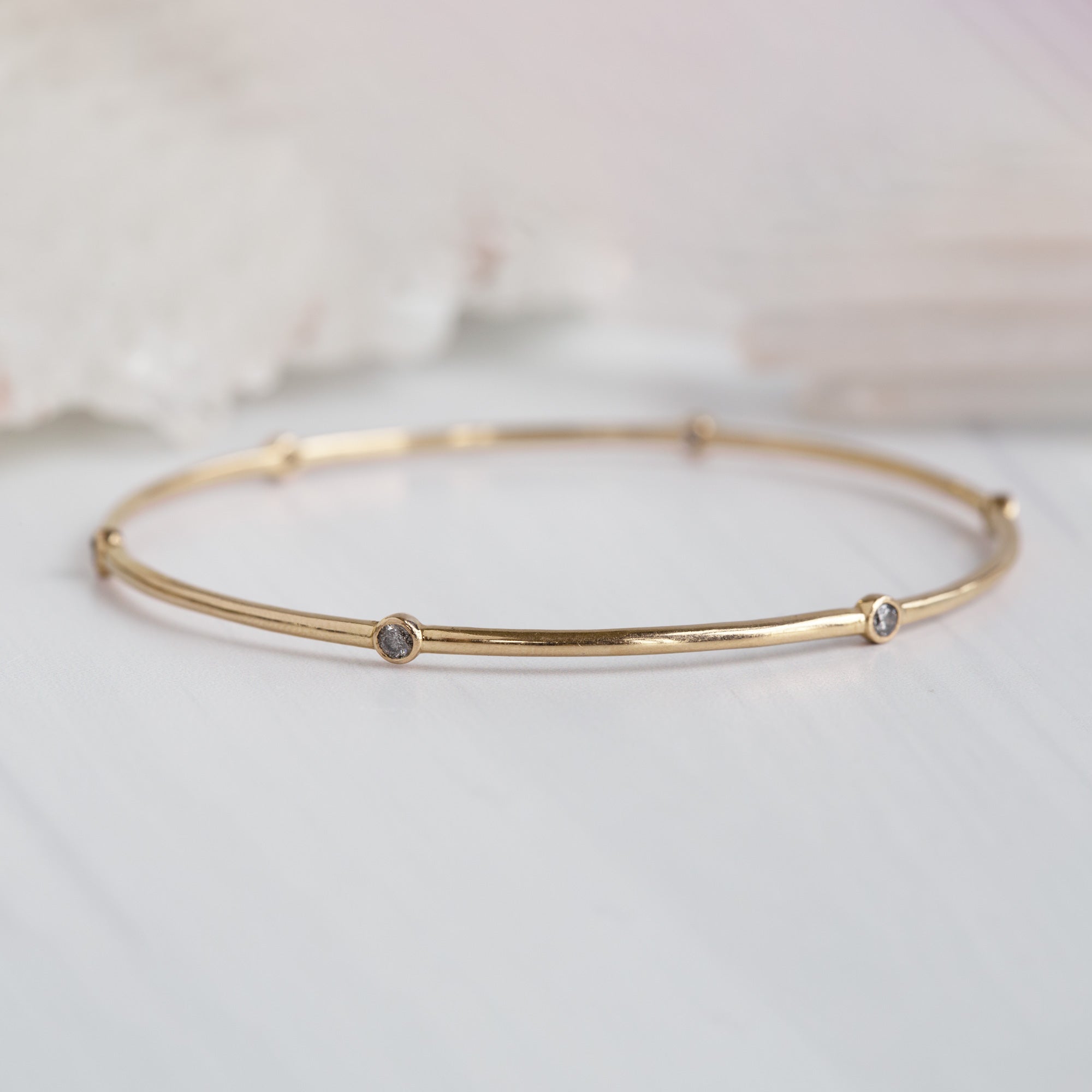 The Salt and Pepper Diamond Constellation Bangle in 14K Yellow Gold on White Marble