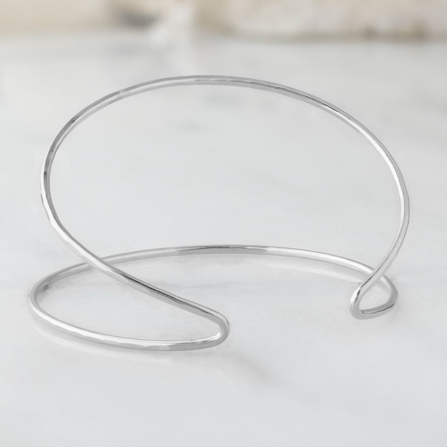 The Arrow Cuff Bracelet in Sterling Silver on White Marble