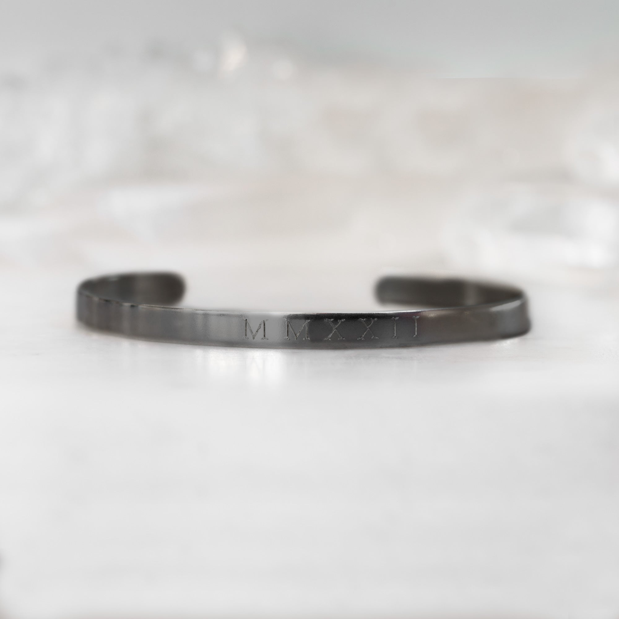 Custom Men's Cuff Bracelet | Oxidized Sterling Silver. Displayed on marble surface with white blurred background.