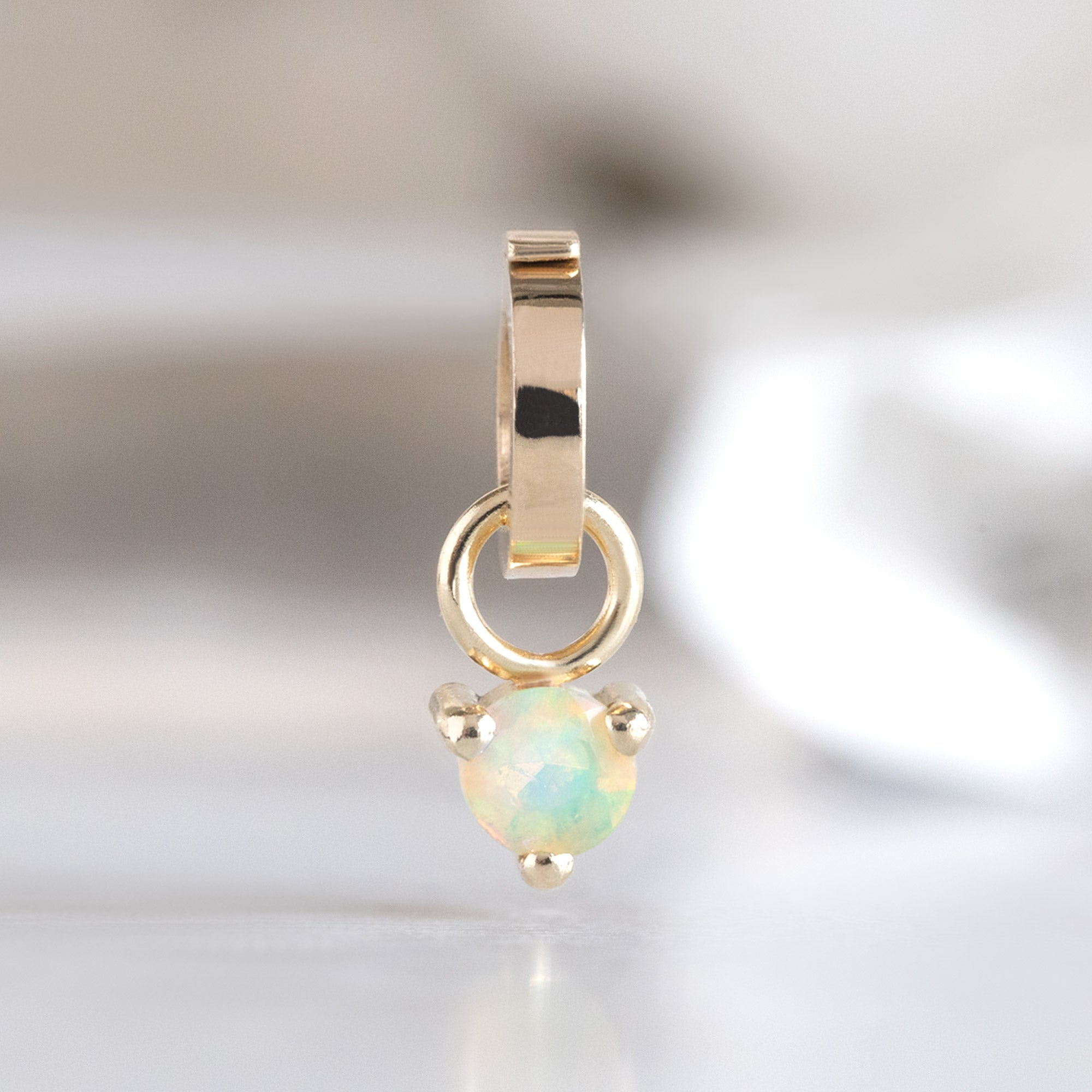 The Opal Birthstone Charm in 10K Yellow Gold on White Marble