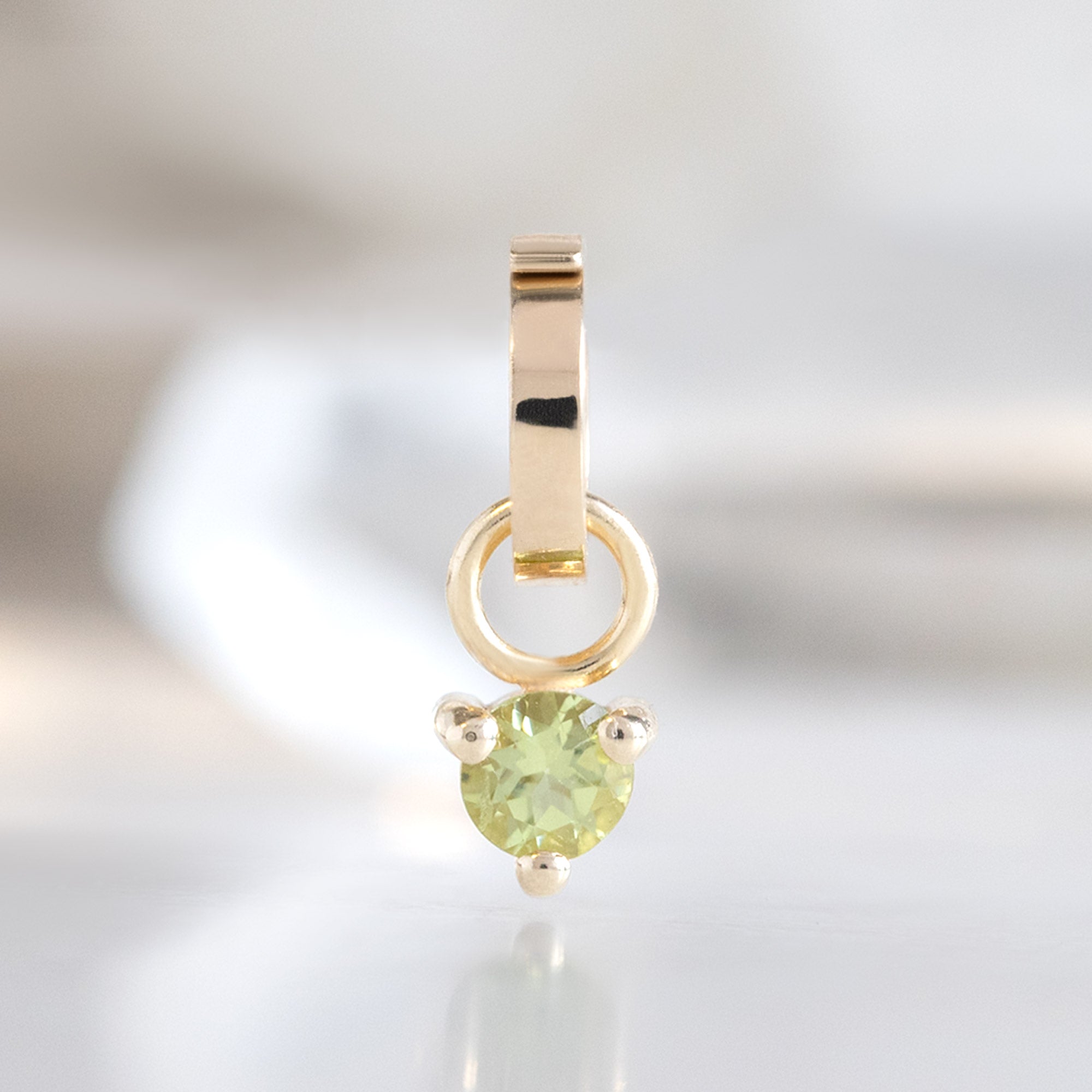 The Peridot Birthstone Charm in 10K Yellow Gold on White Marble