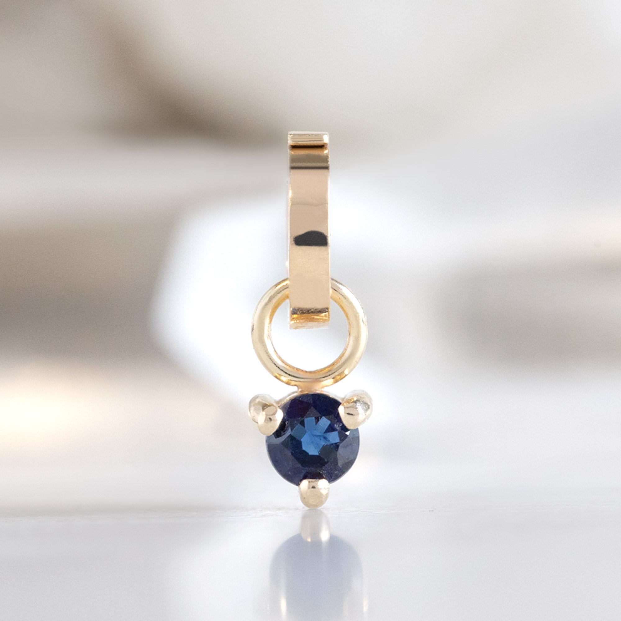 The Sapphire Birthstone Charm in 10K Yellow Gold on White Marble