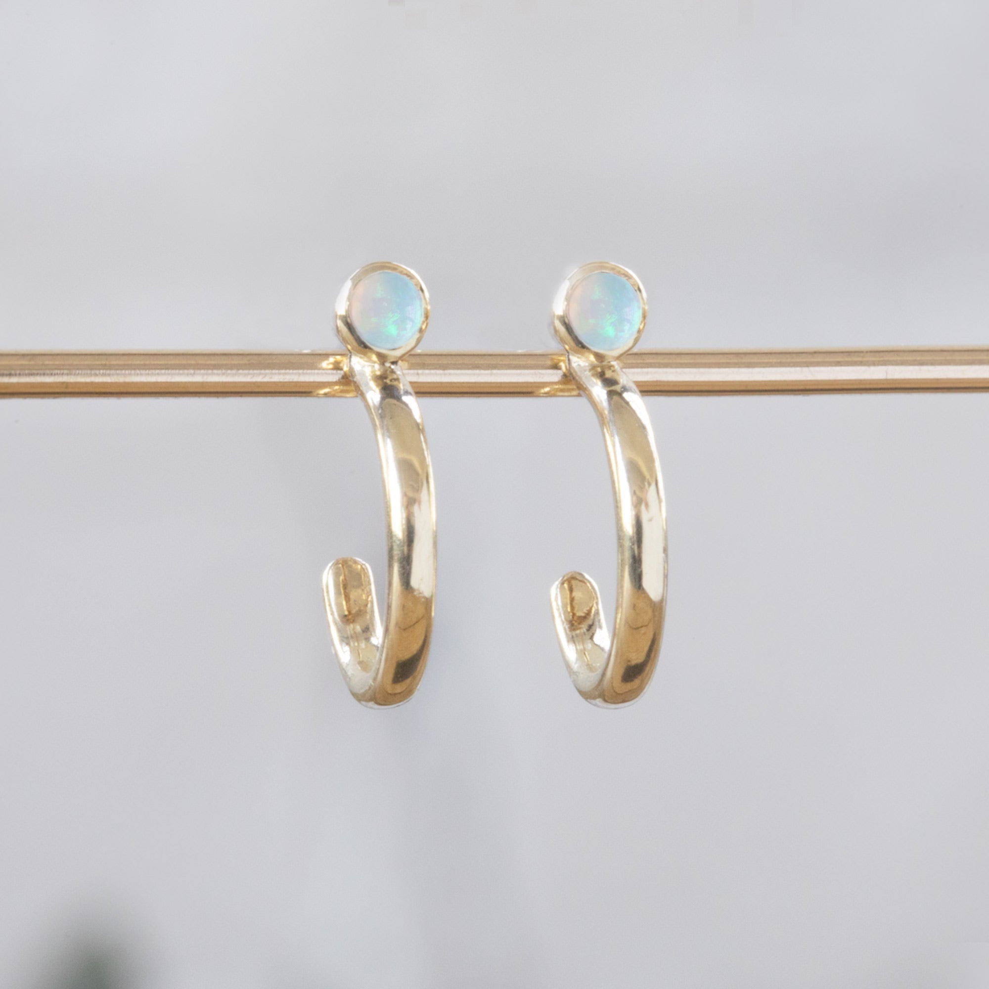Custom Opal Birthstone Hoop Earrings | 14K Yellow Gold displayed on holding bar.