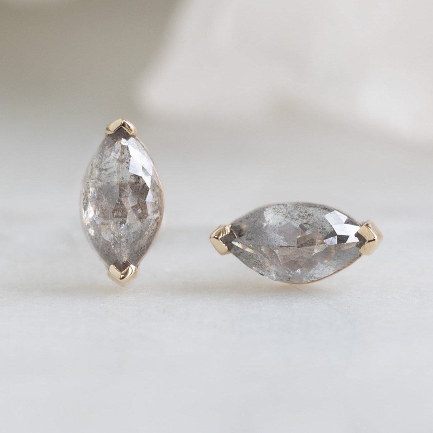 The Salt and Pepper Diamond Eye Stud Earrings in 14K Yellow Gold on White Marble