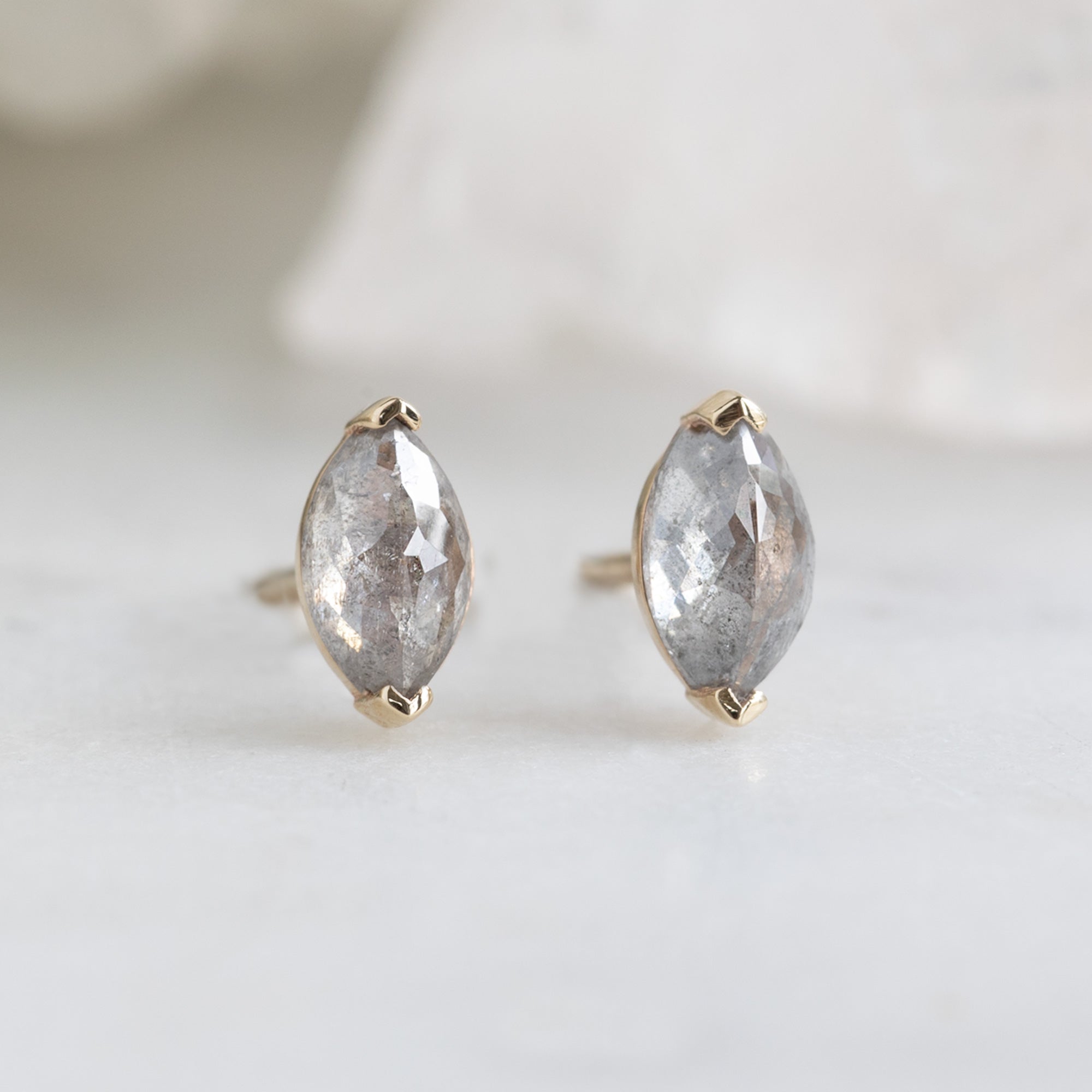 The Salt and Pepper Diamond Eye Stud Earrings in 14K Yellow Gold on White Marble