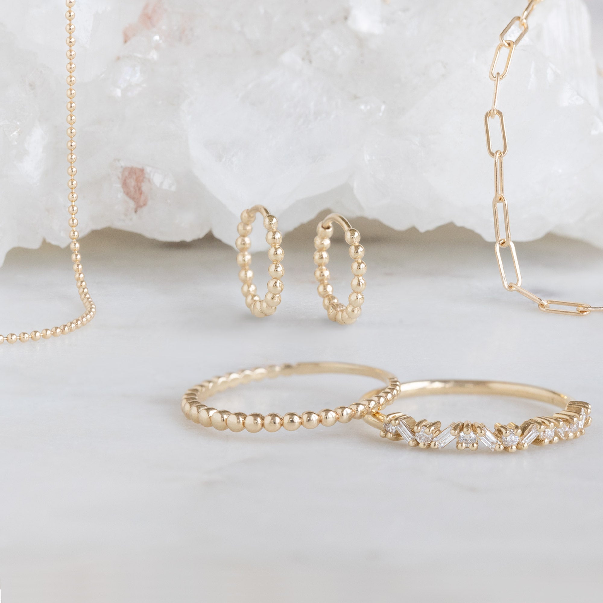 Yellow Gold Beaded Fine Jewelry Collection on White Marble