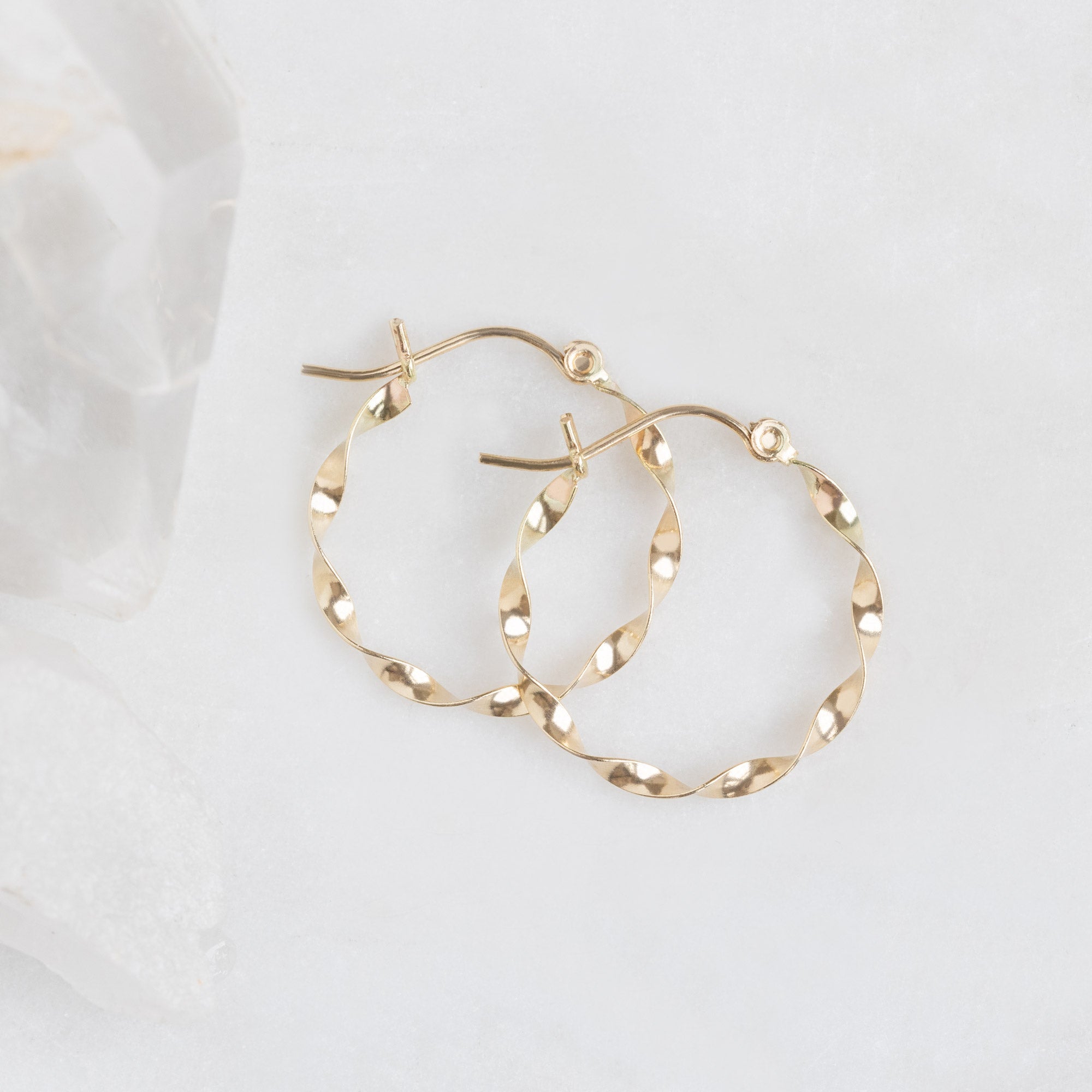 The Ribbon Hoops in 14K Yellow Gold laying on white marble