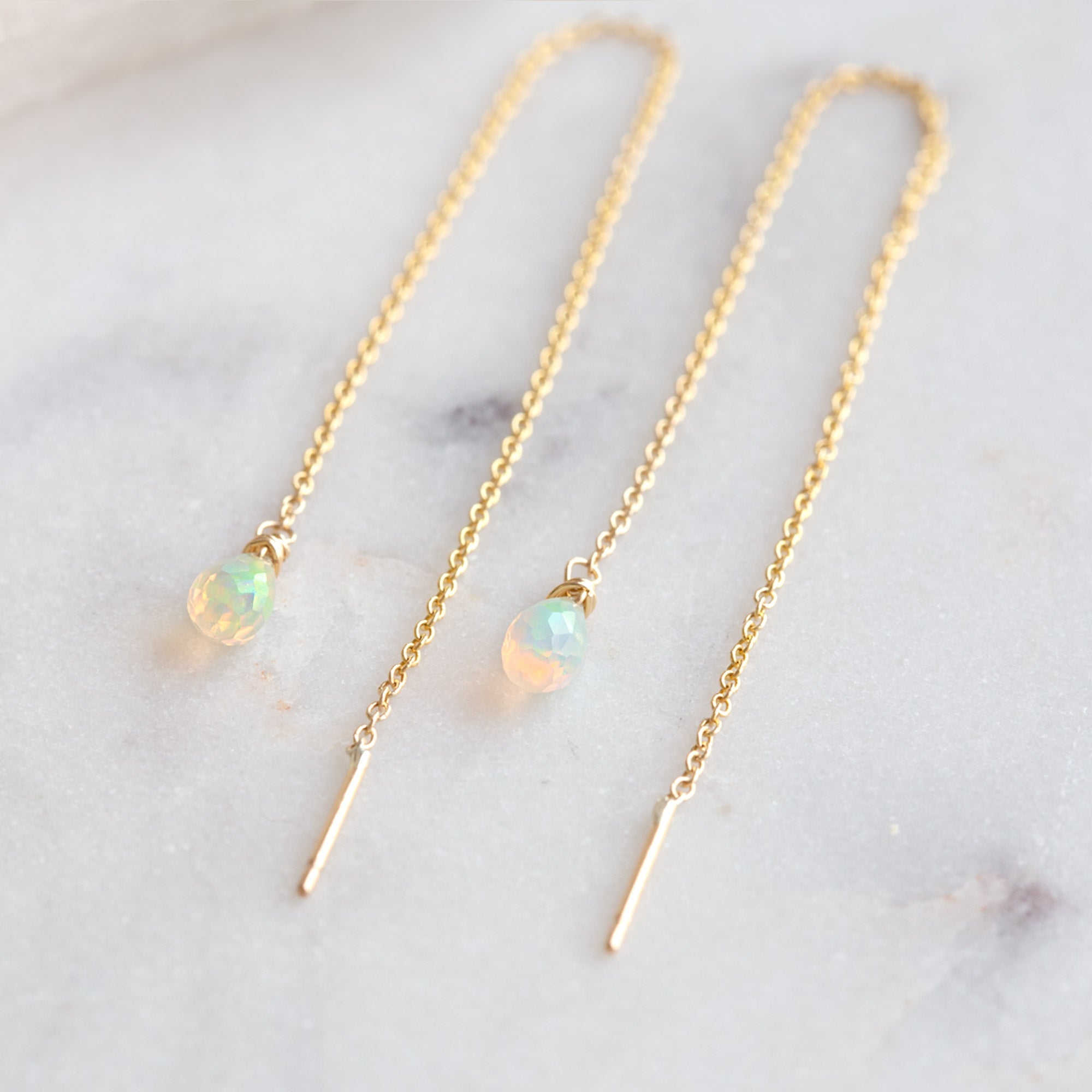 Opal Thread Earrings in Yellow Gold Filled laying on white marble