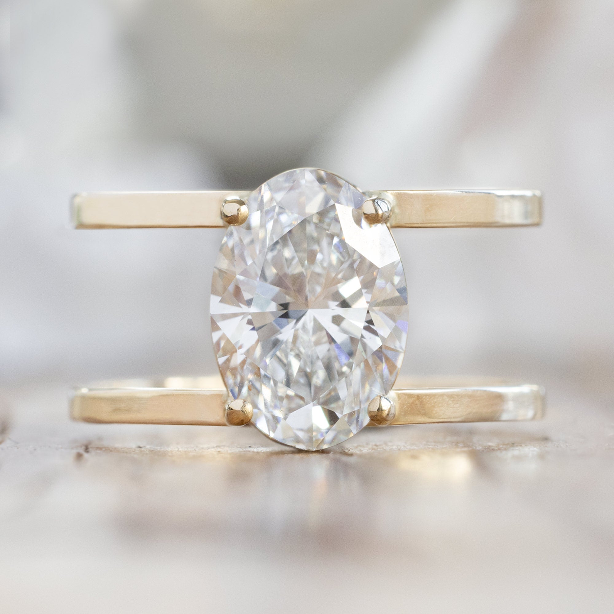 An oval-cut lab grown white diamond in a 14K yellow gold band, with a double band setting.