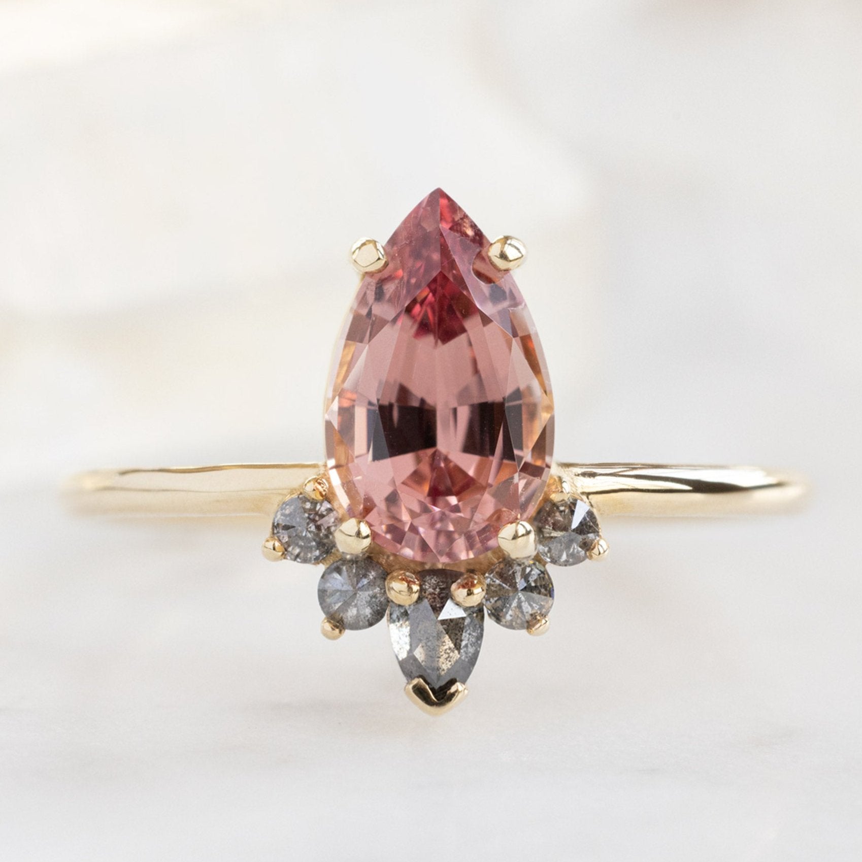 The Aster Ring with a 1.59ct Pear Garnet in 14K Yellow Gold on White Marble