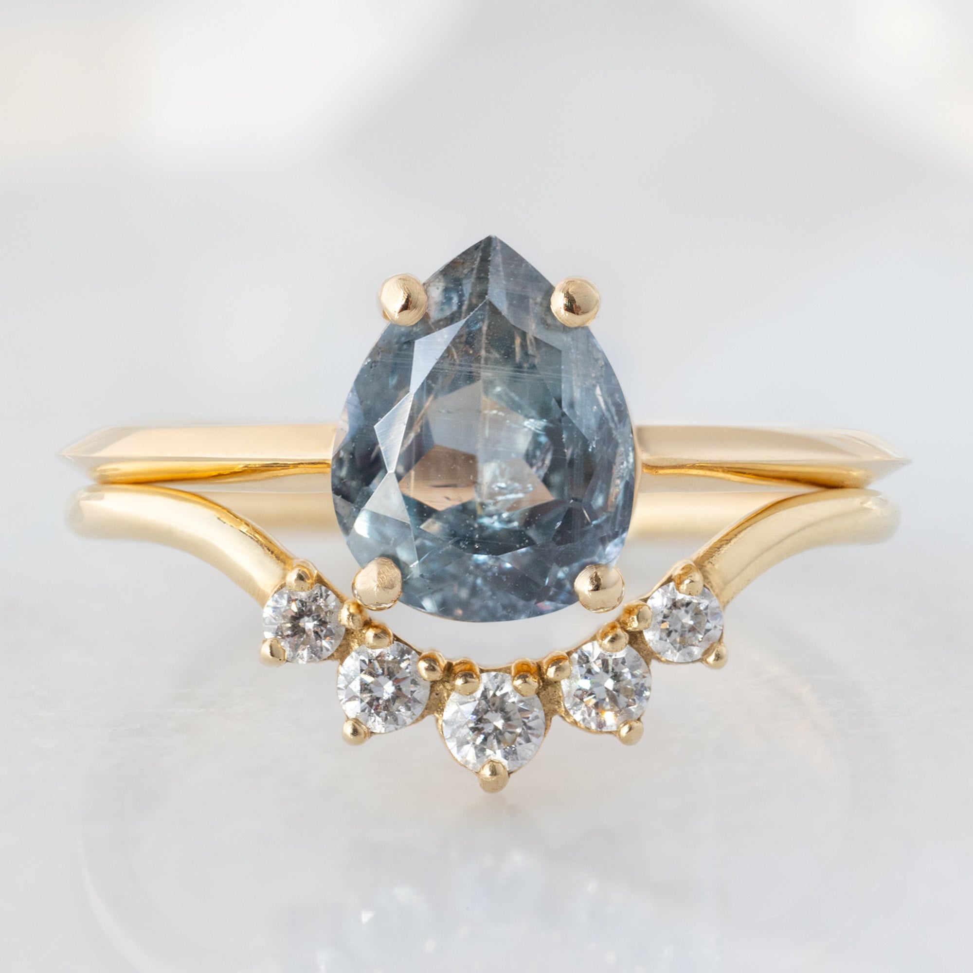 The Bryn Ring with a 1.42ct Pear Cut Blue Sapphire in 14K Yellow Gold on  Stacked with the Round White Diamond Sunburst Stacking Band