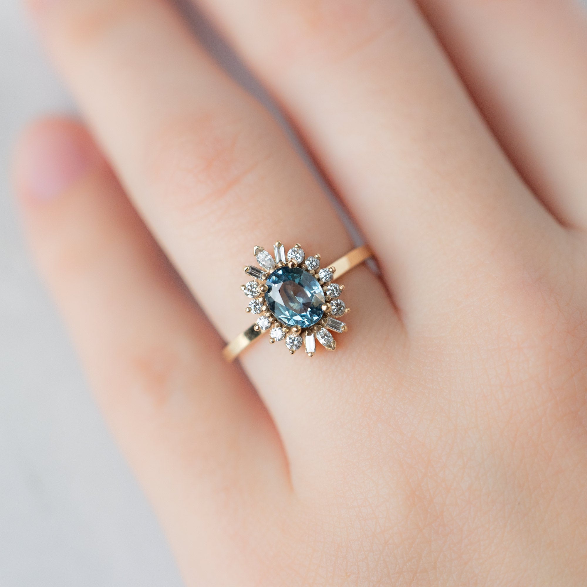 The Camellia Ring with a 1.32ct Oval Blue Montana Sapphire in 14K Yellow Gold on Model