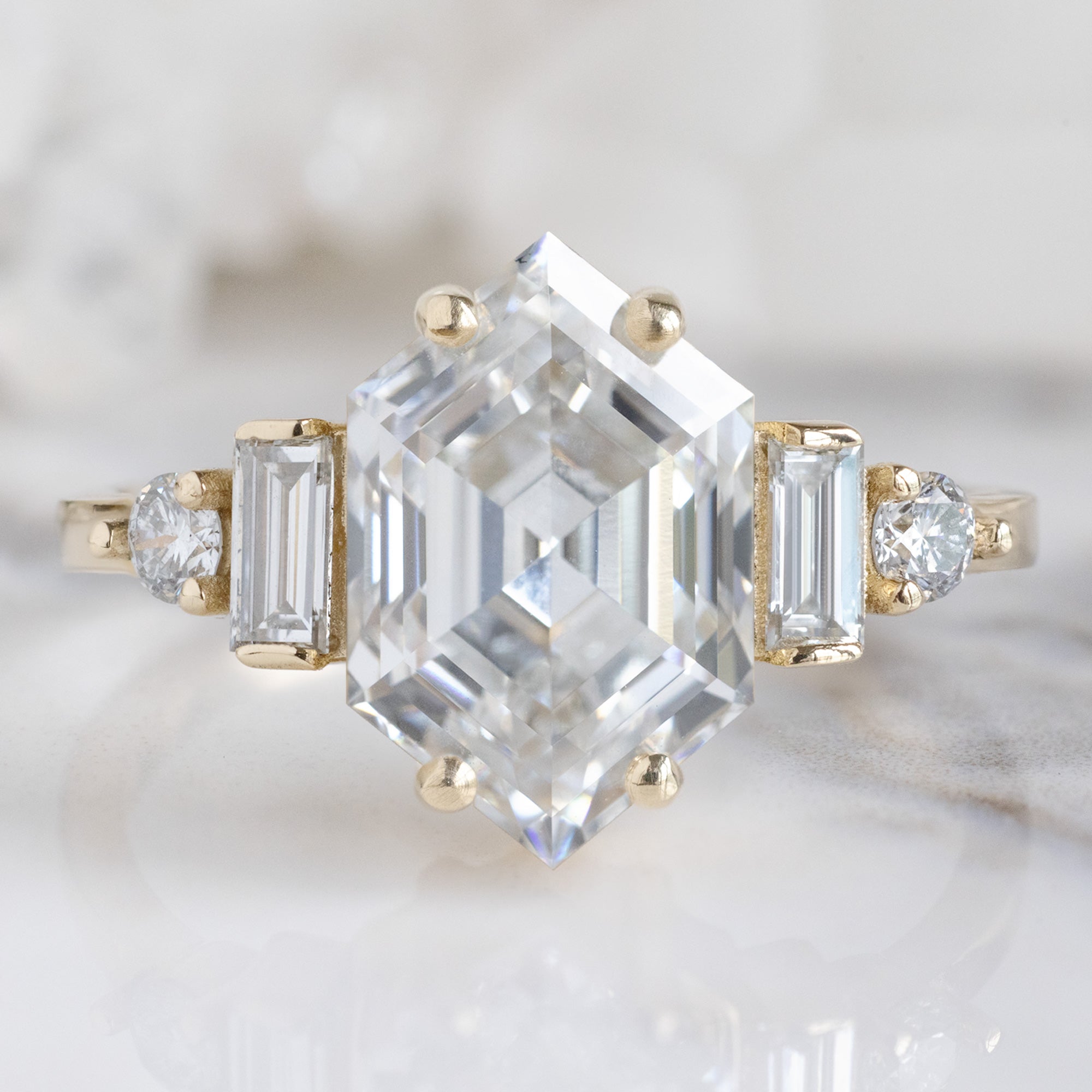 The Primrose Ring with a 2.64ct Hexagon Lab Grown White Diamond in 14K Yellow Gold on White Marble