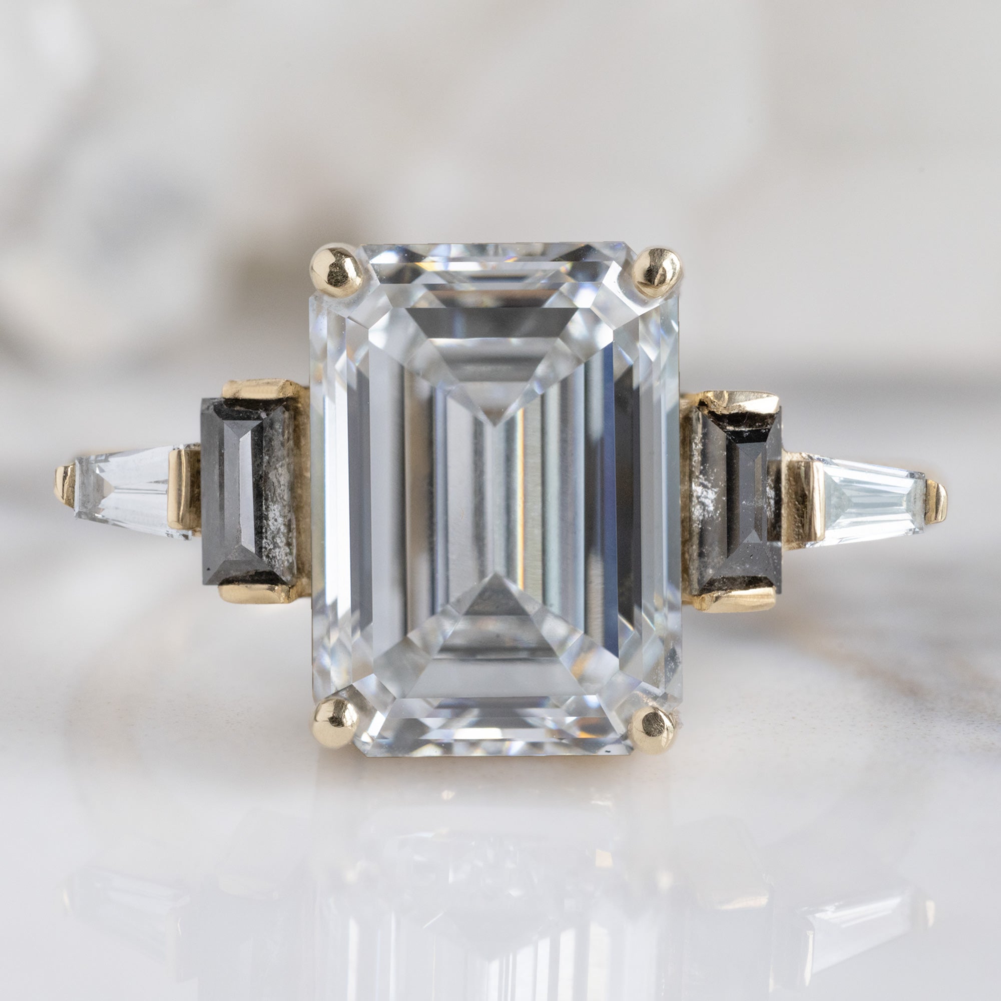 The Deco Ring with a 3.39ct Emerald Cut Lab Grown White Diamond in 14K Yellow Gold on White Marble