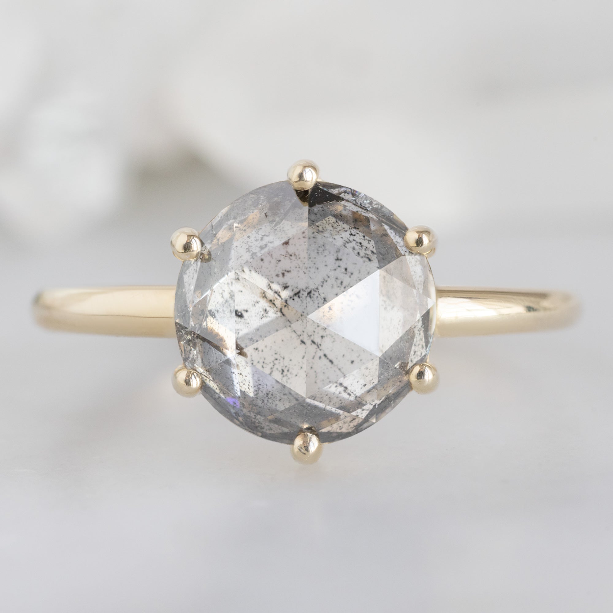 The Rose Ring with a 2.55ct Round Lab Grown Salt and Pepper Diamond in 14K Yellow Gold on White Marble