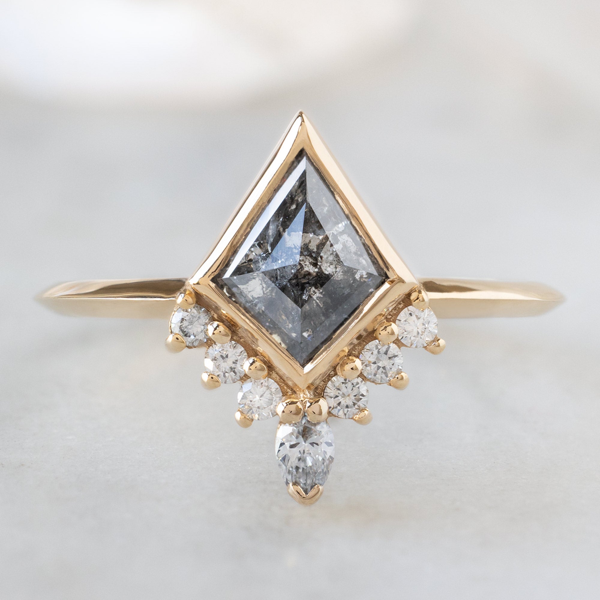 The Aster Ring with a Salt and Pepper Kite Diamond in 14K Yellow Gold on White Marble