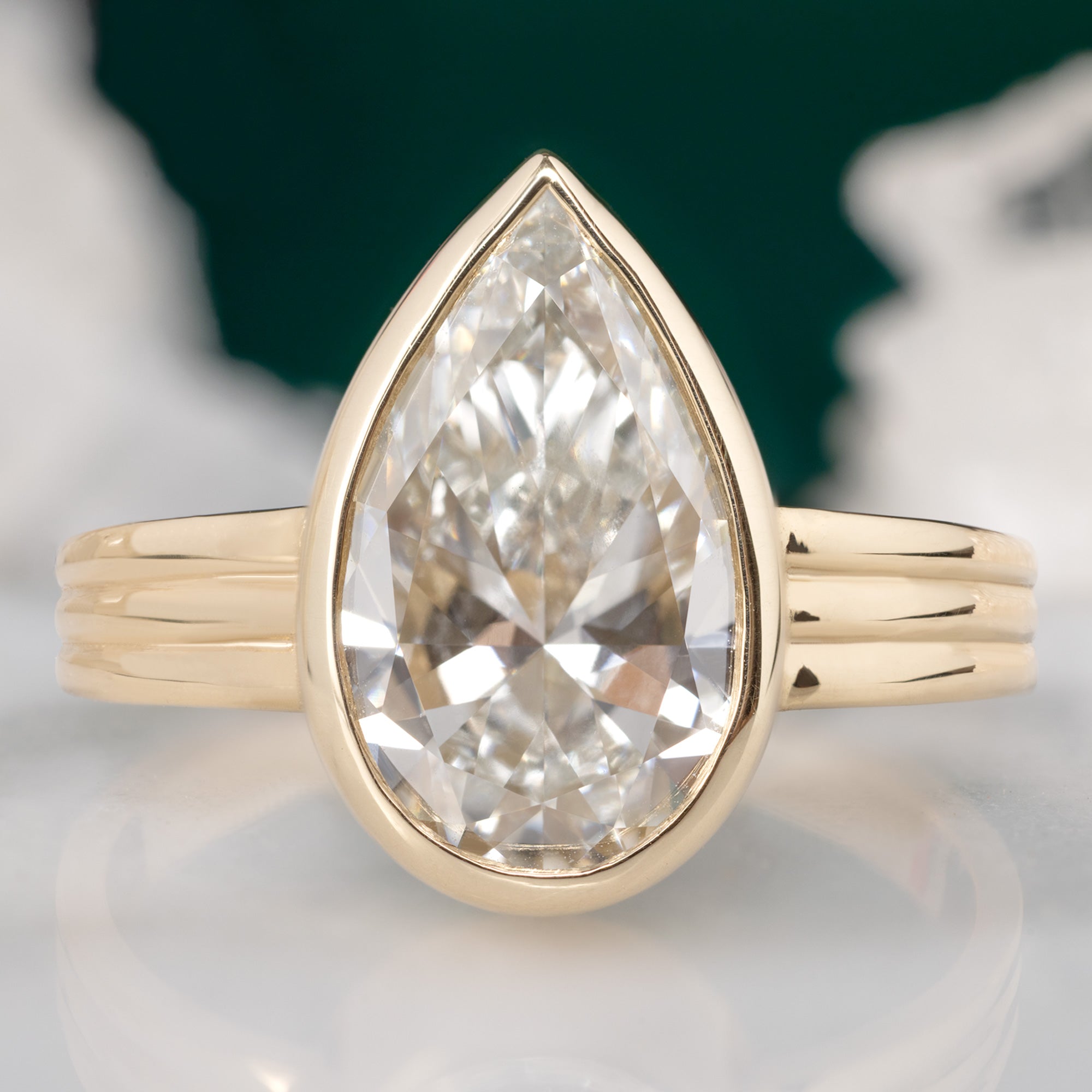 The Stratum Ring with a 3.02ct Pear Lab Grown White Diamond in 14K Yellow Gold with green background