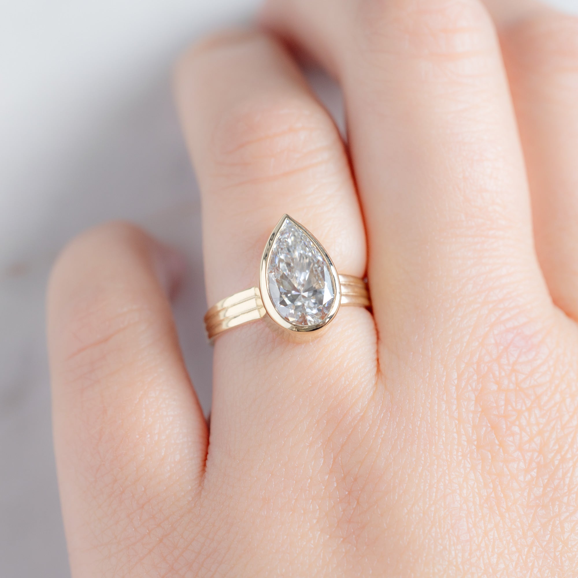The Stratum Ring with a 3.02ct Pear Lab Grown White Diamond in 14K Yellow Gold on Model