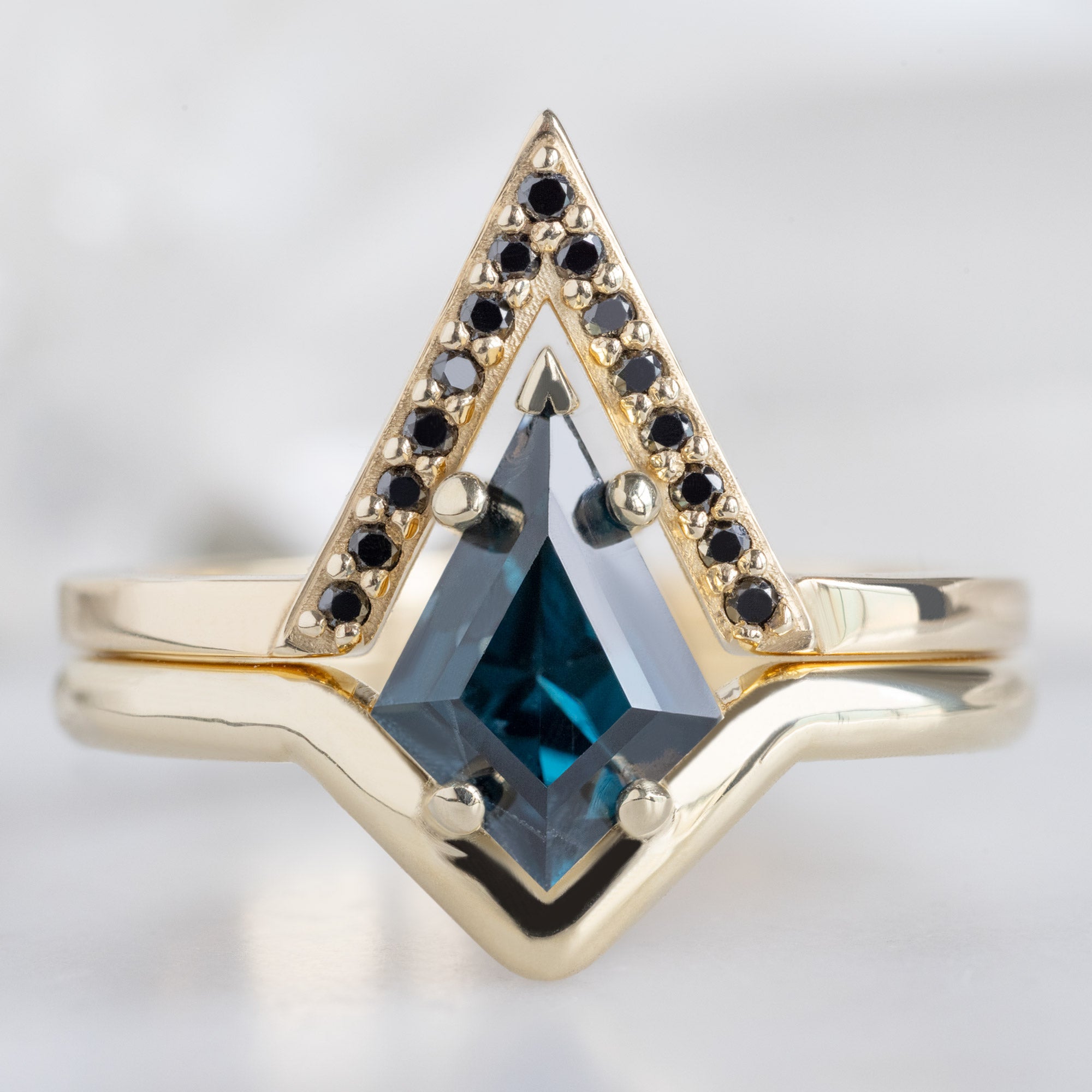 The Wave Ring with a 1.08ct Kite Blue Spinel in 14k Yellow Gold Stacked with the Black Diamond Pavé Pointed Peak Stacking Band