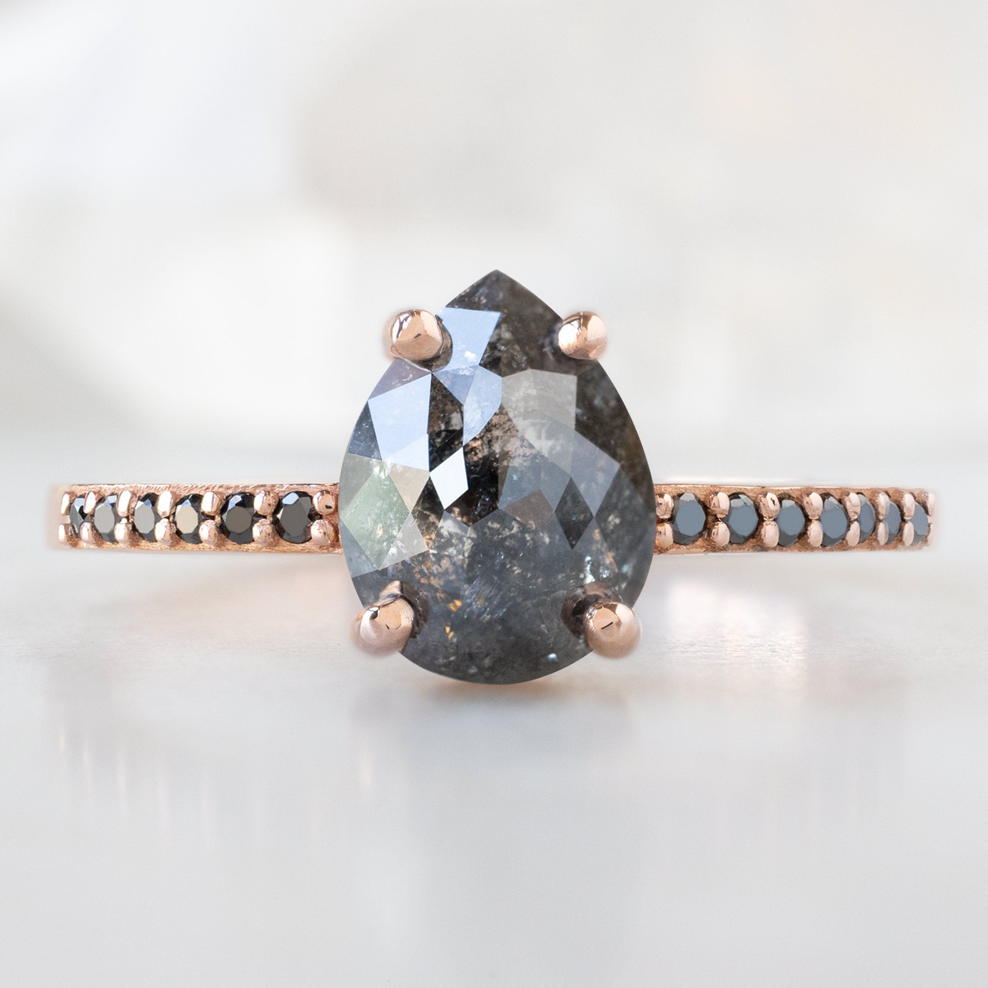 The Willow Ring with a 1.59ct Pear Black Diamond in 14K Rose Gold on White Marble