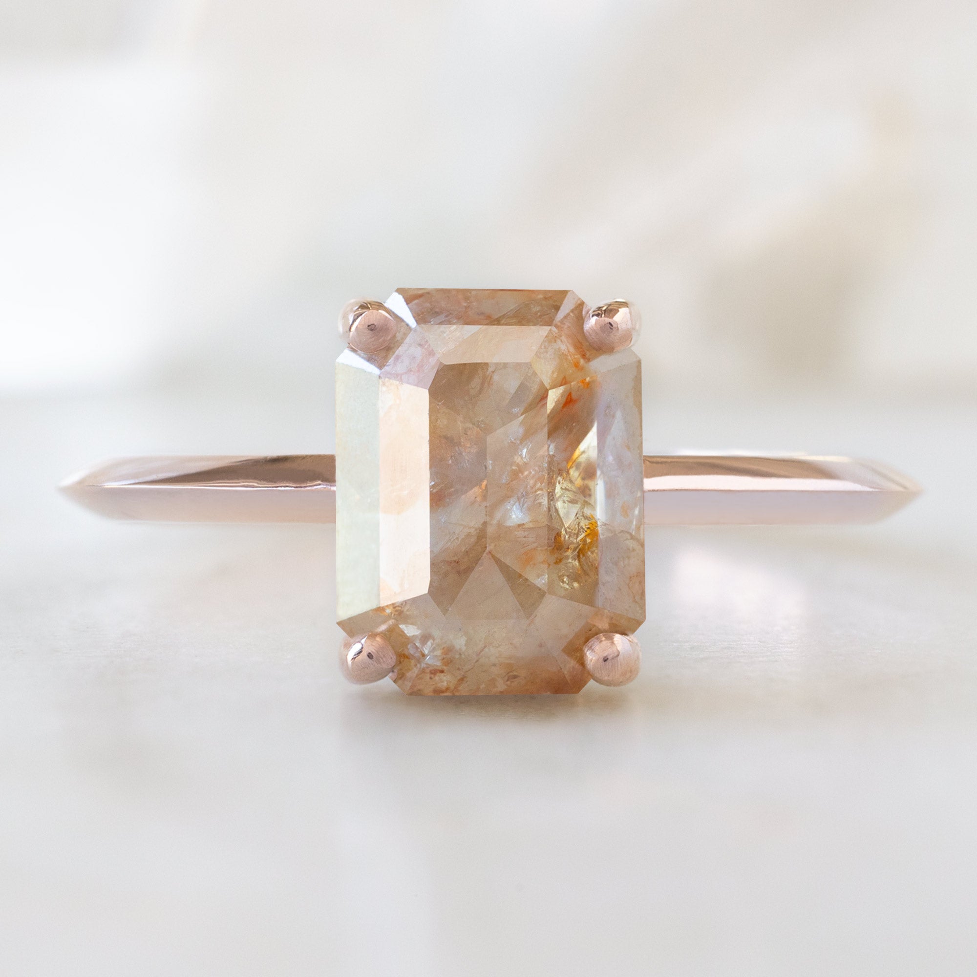The Bryn Ring with an Emerald-Cut Red Diamond in 14K Rose Gold on White Marble