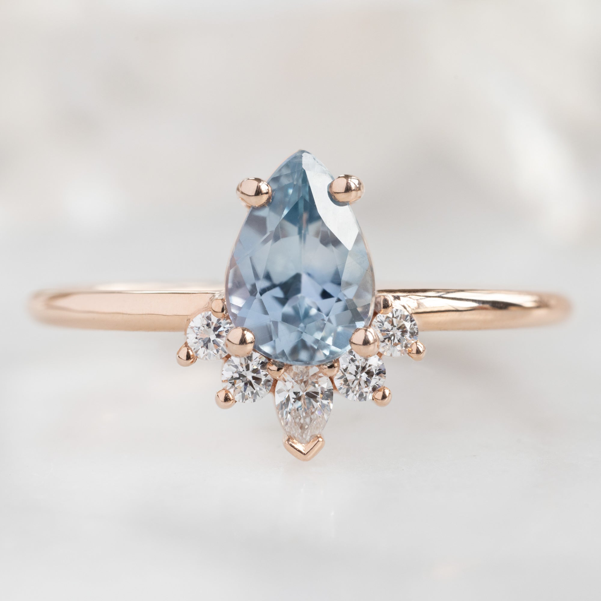 The Aster Ring with a Pear Blue Sapphire in 14k Rose Gold on White Marble