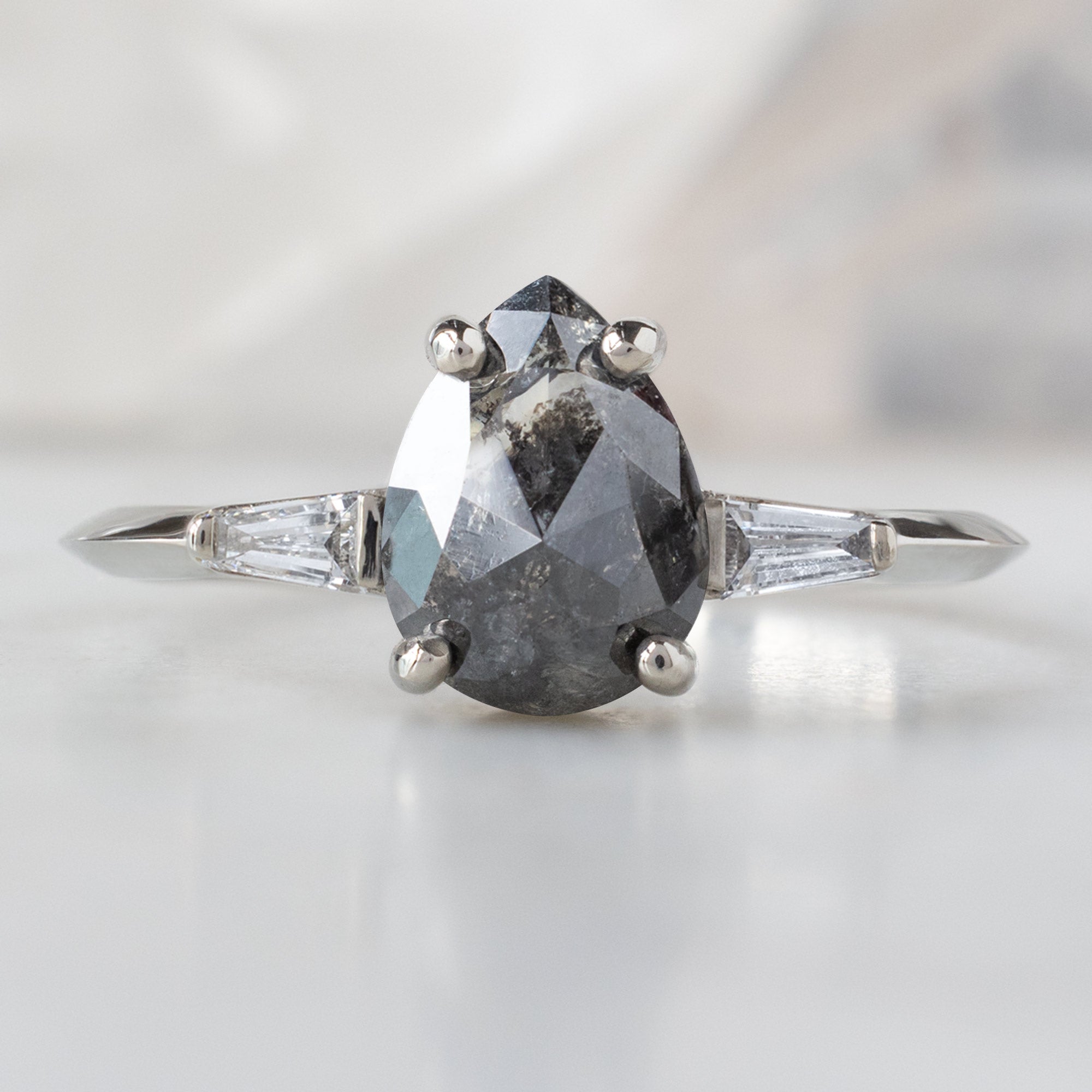 The Ash Ring with a 1.24ct Pear Black Diamond in 14K White Gold on White Marble