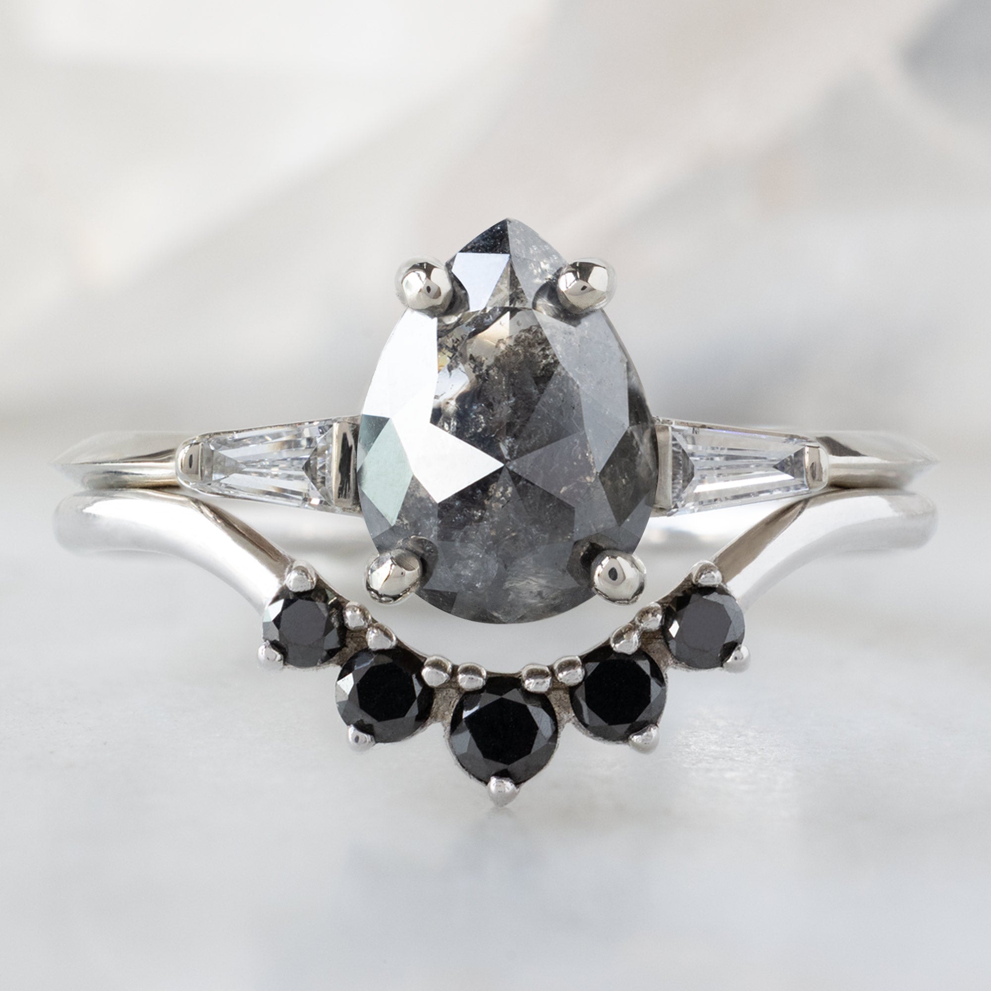 The Ash Ring with a 1.24ct Pear Black Diamond in 14K White Gold Stacked with the Round Black Diamond Sunburst Stacking Band