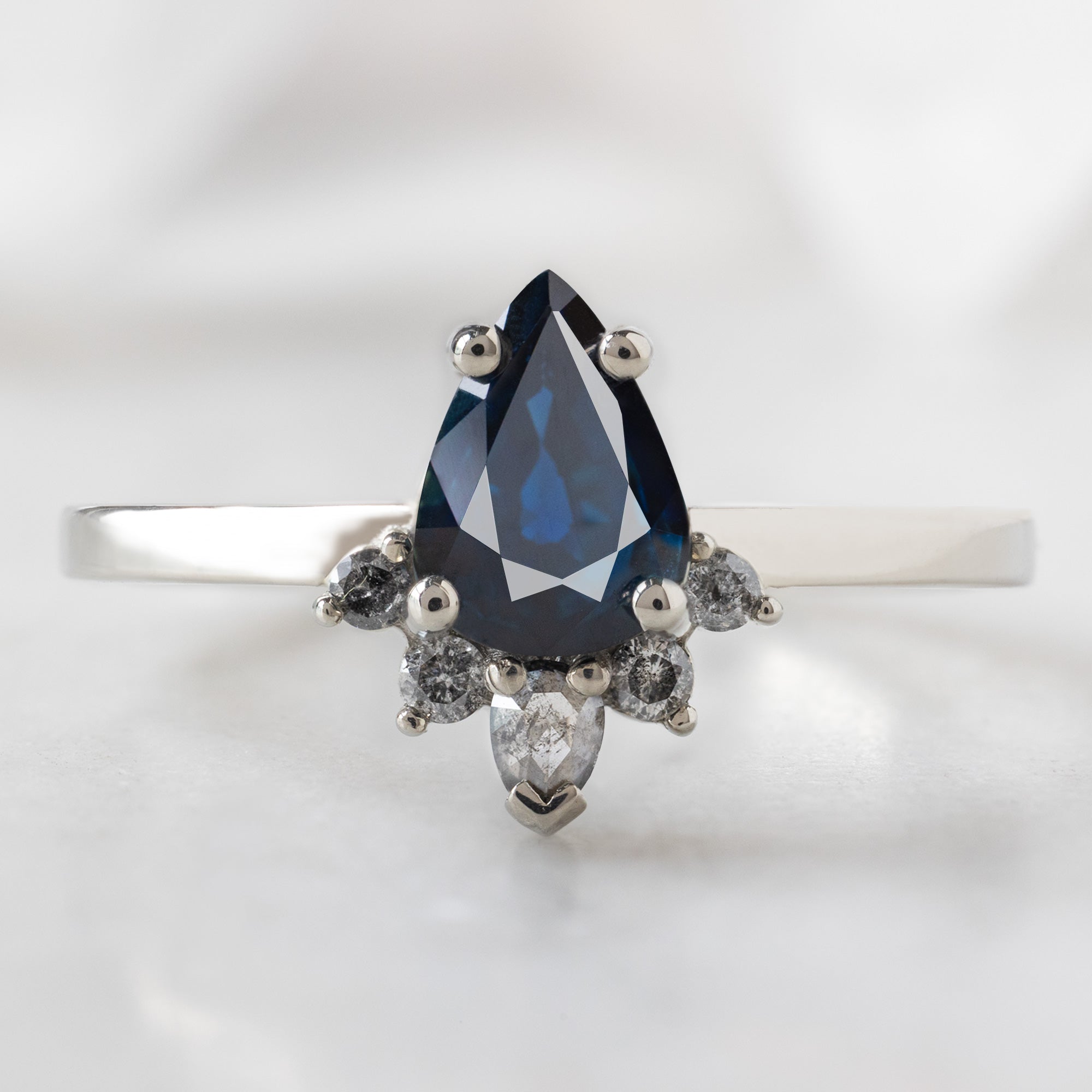 The Aster Ring with a 0.90ct Pear Blue Sapphire in 14K White Gold on White Background