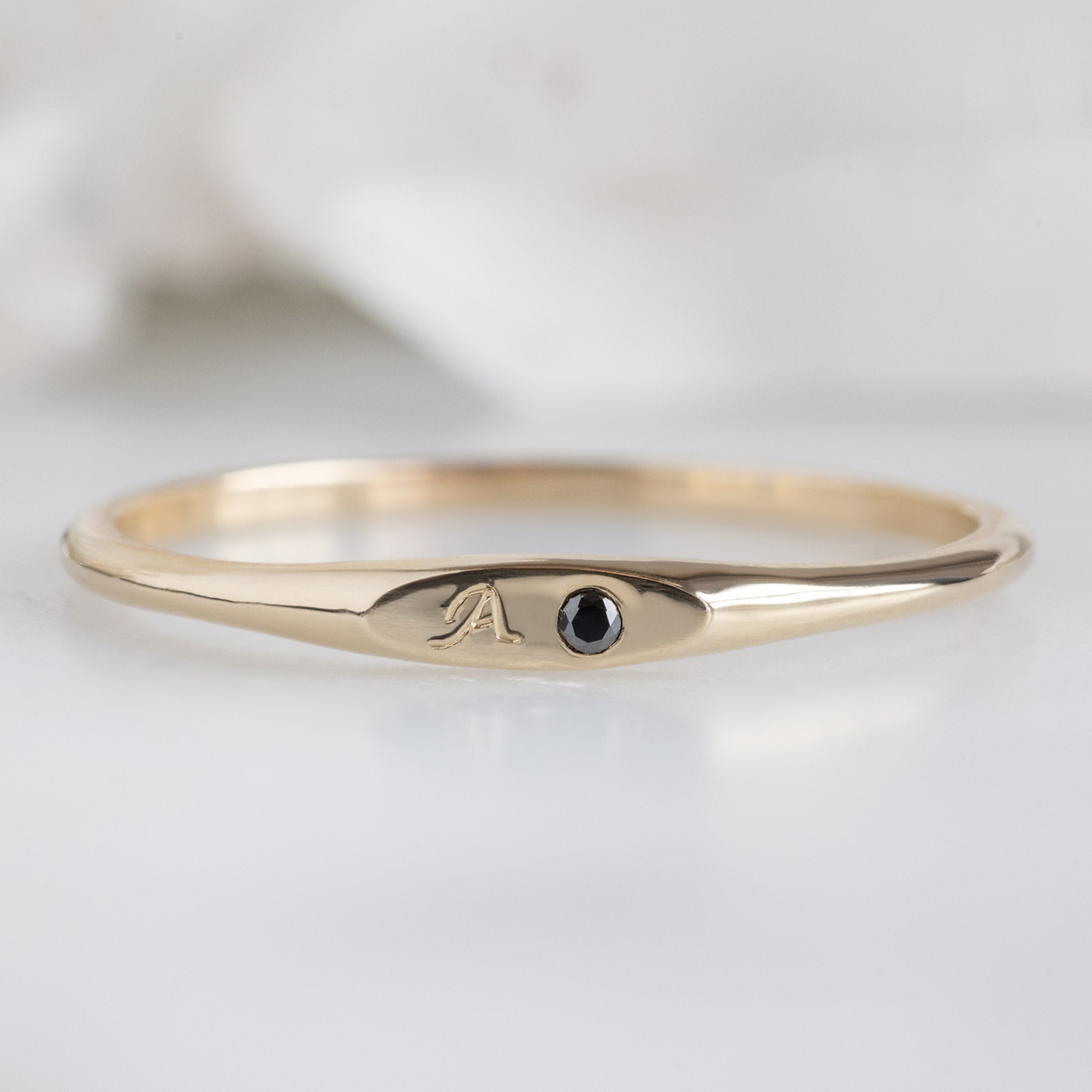 The Teensy Black Diamond Signet Ring in 10K Yellow Gold on White Marble