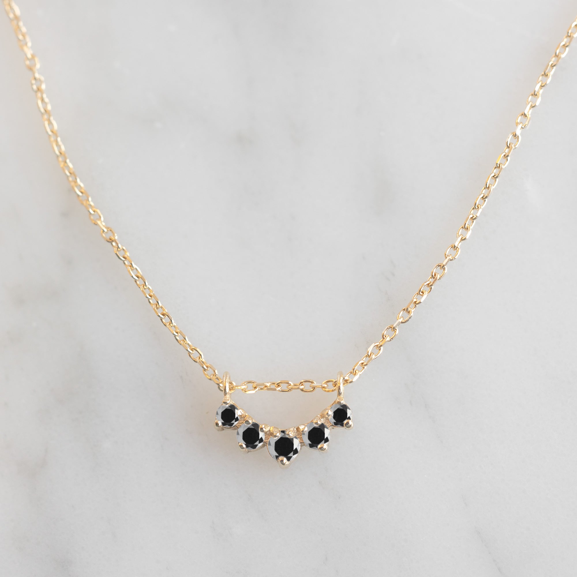 Custom Black Diamond Sunburst Necklace | 10K Yellow Gold displayed on marble surface.