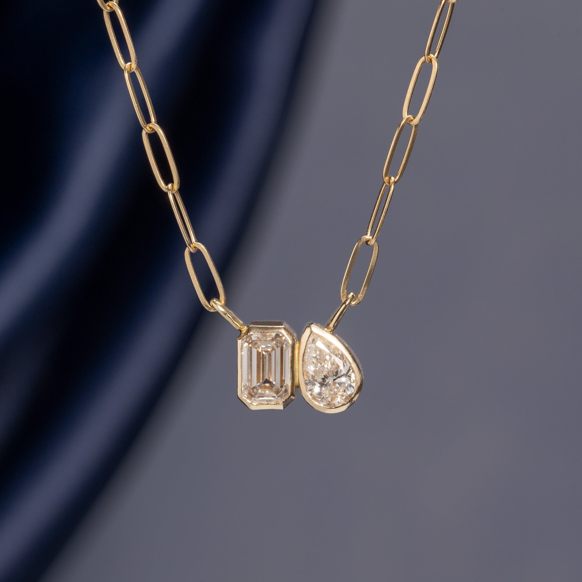 The You and Me Diamond Necklace in 10K Yellow Gold hanging in front of muted blue background