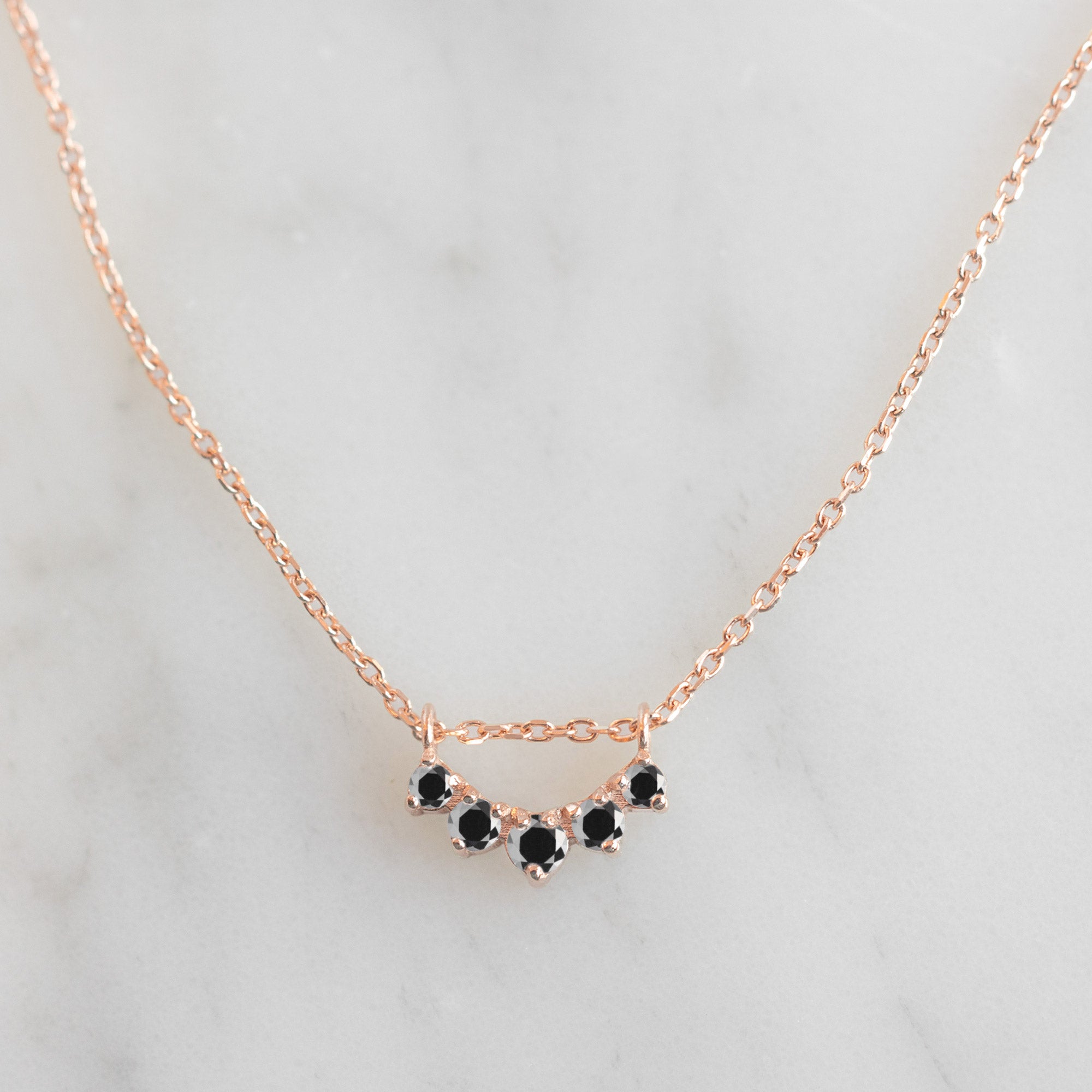 Custom Black Diamond Sunburst Necklace | 10K Rose Gold displayed on marble surface.
