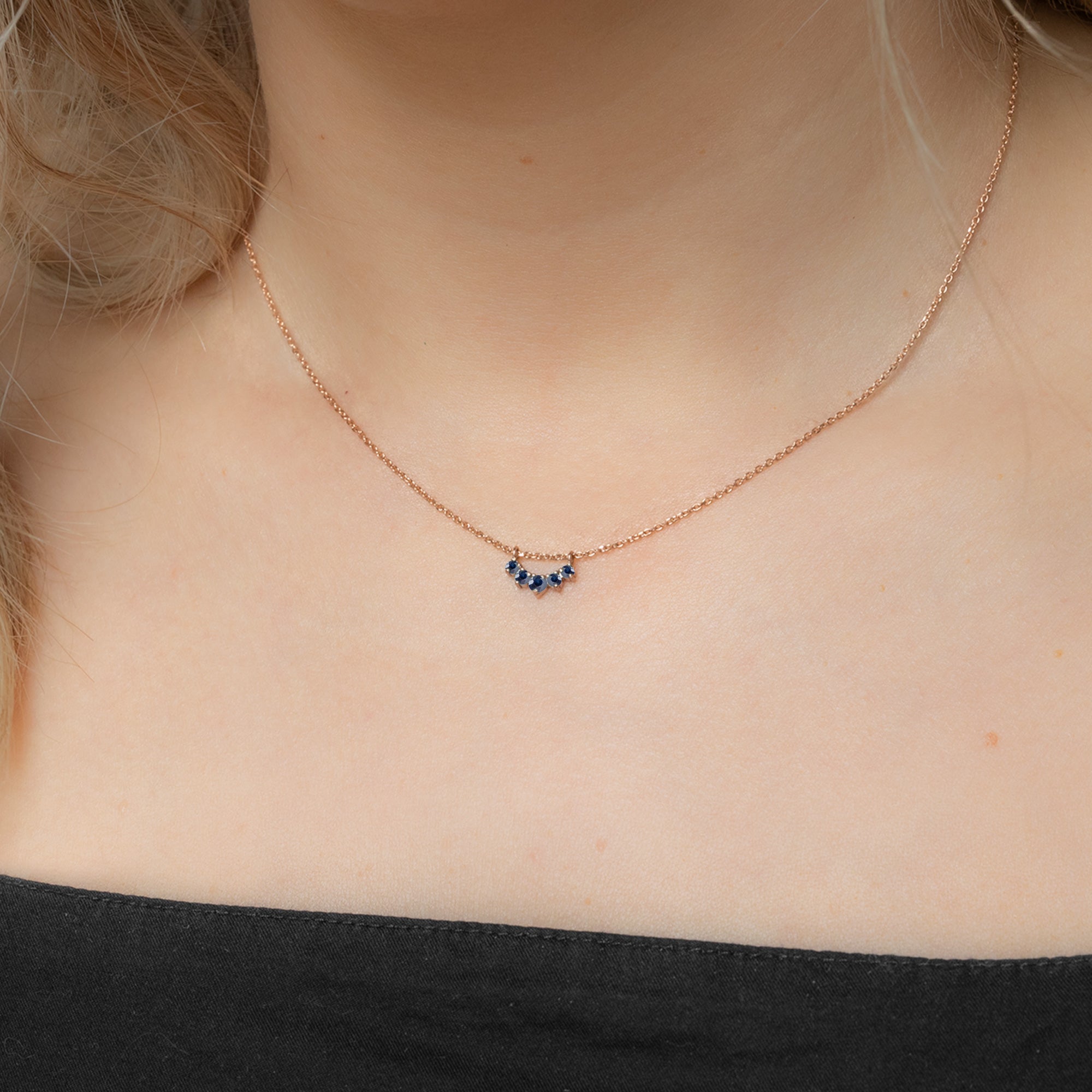 Custom Blue Sapphire Gemstone Sunburst Necklace | 10K Rose Gold displayed on model's neck.
