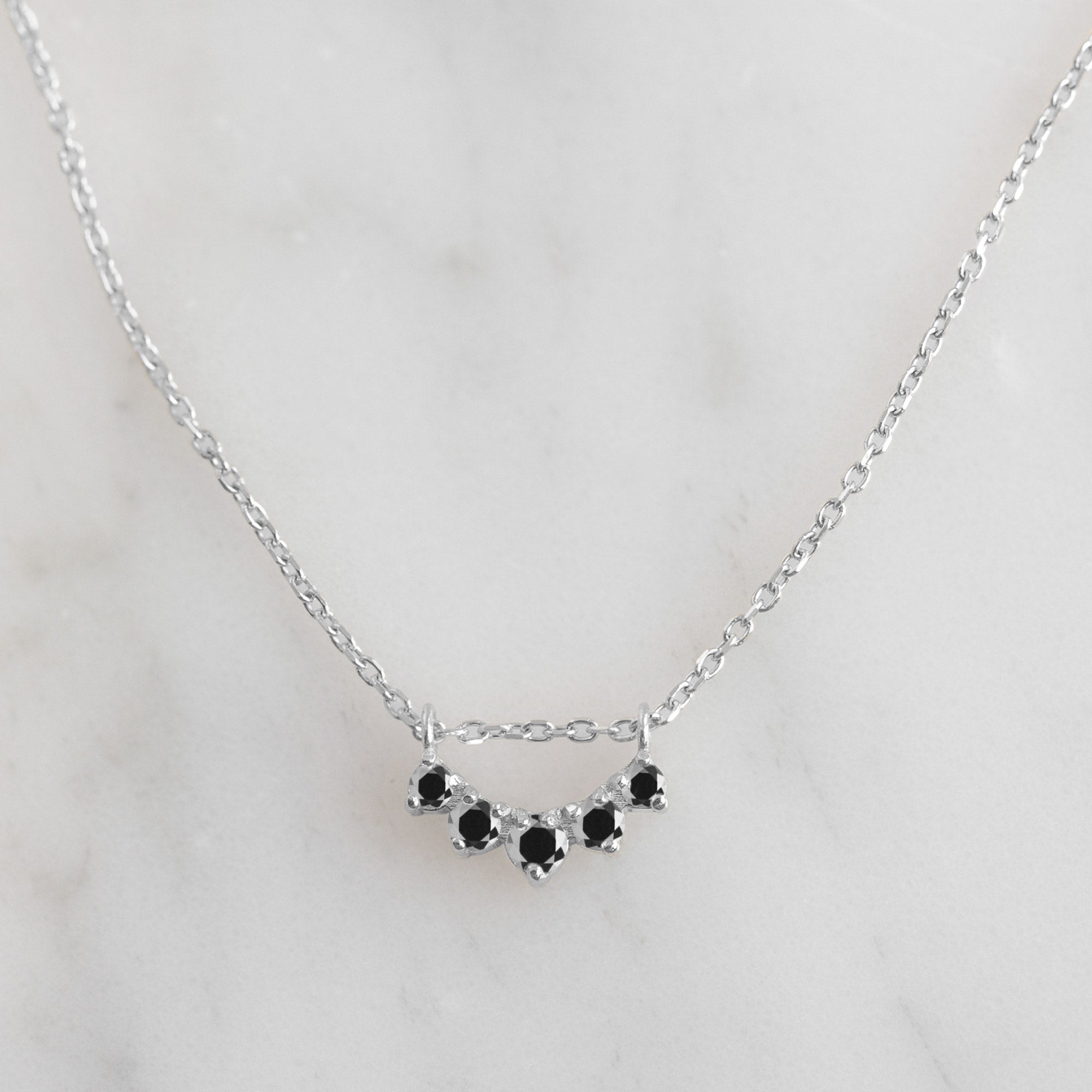 Custom Black Diamond Sunburst Necklace | 10K White Gold displayed on marble surface.
