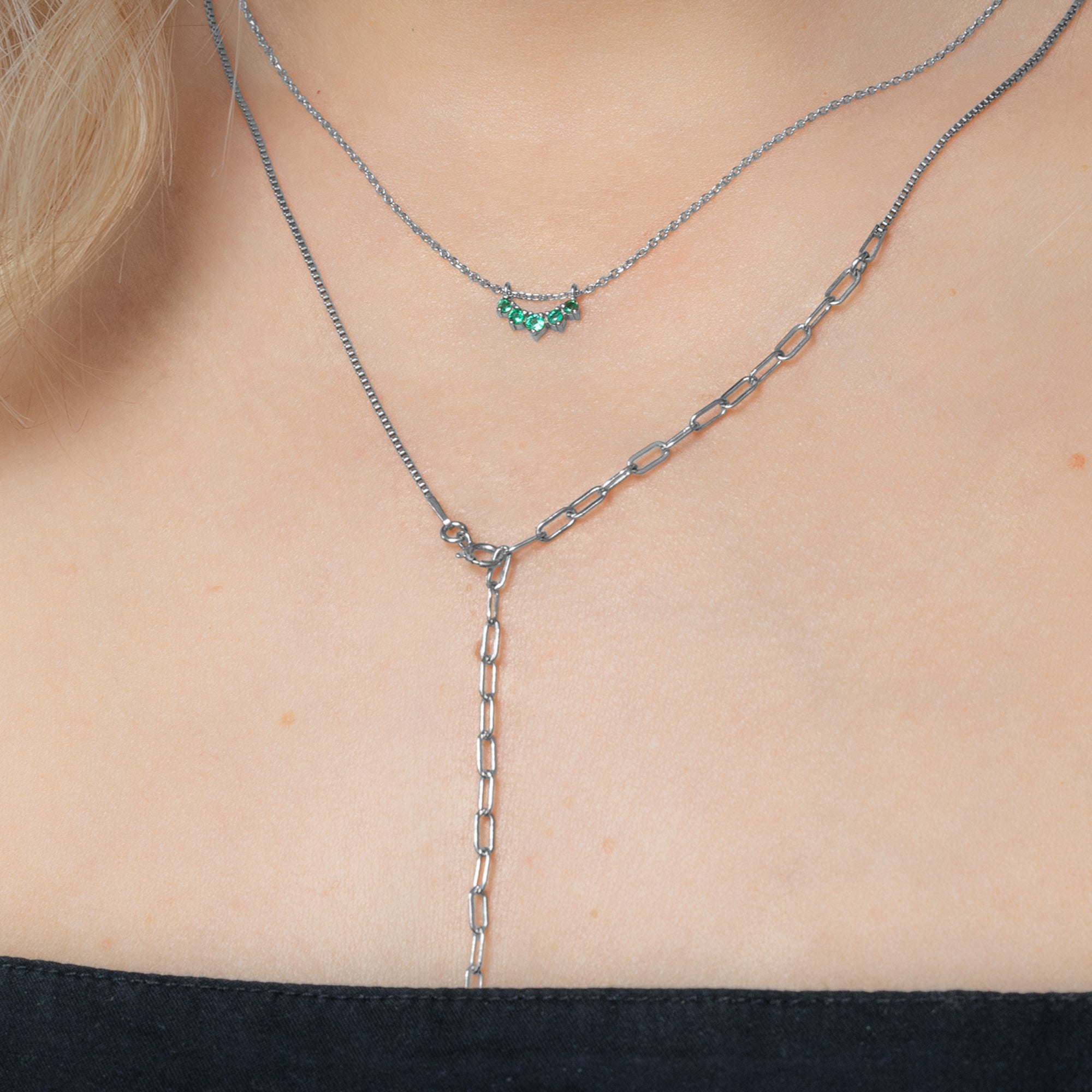 Custom Emerald Gemstone Sunburst Necklace | 10K White Gold. Displayed on model's neck paired with another chain.