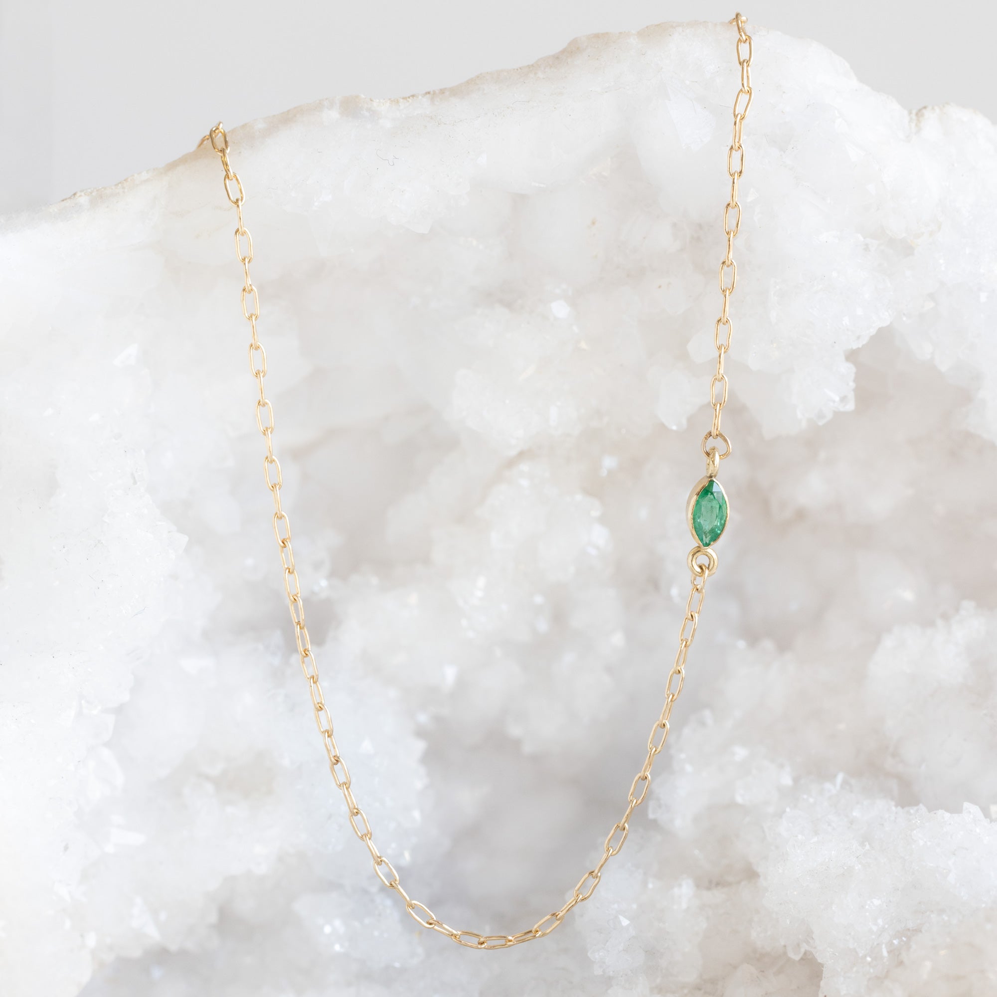 The Teensy Emerald Necklace in Yellow Gold Filled hanging on white crystal