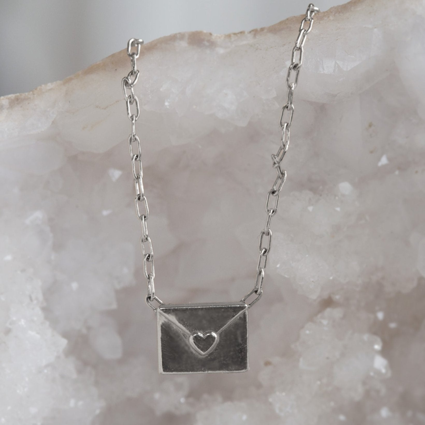 sterling silver necklace featuring a loveletter shaped pendant hanging on white geode