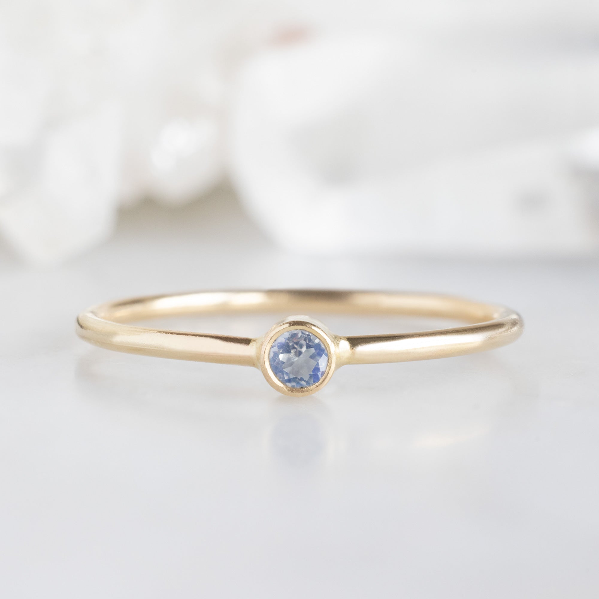 Custom Moonstone Birthstone Stacking Ring | 10K Yellow Gold with blurred background.