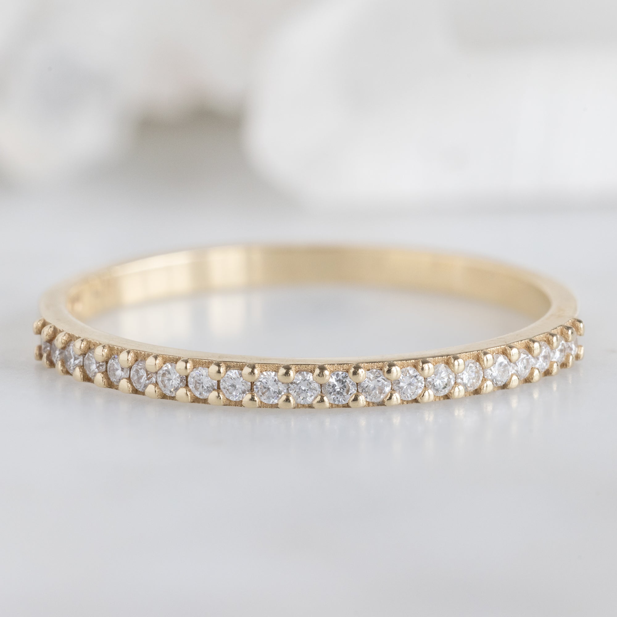 The White Diamond Pavé Wedding Band in 14K Yellow Gold on White Marble Tile