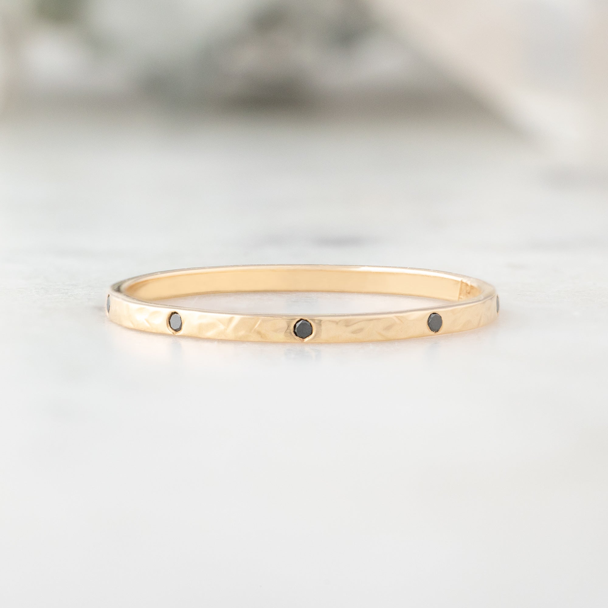 Black Diamond Eternity Band in 14K Yellow Gold on White Marble
