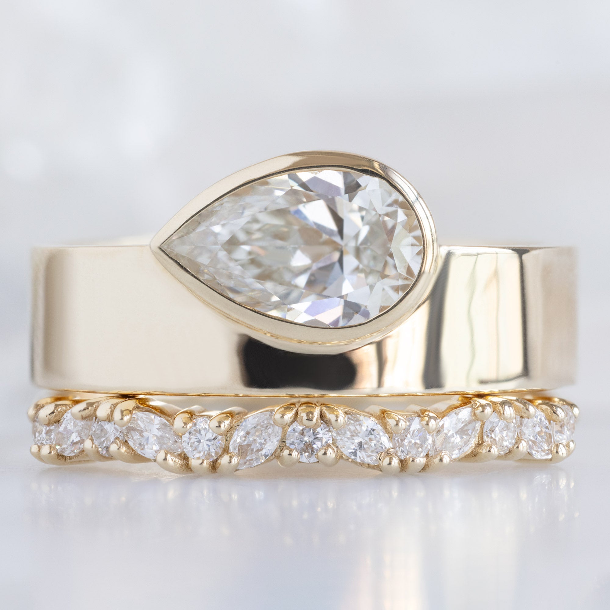 The Marquise Confetti Wedding Band in 14K Yellow Gold Stacked with White Diamond Pear Cigar Band Engagement Ring