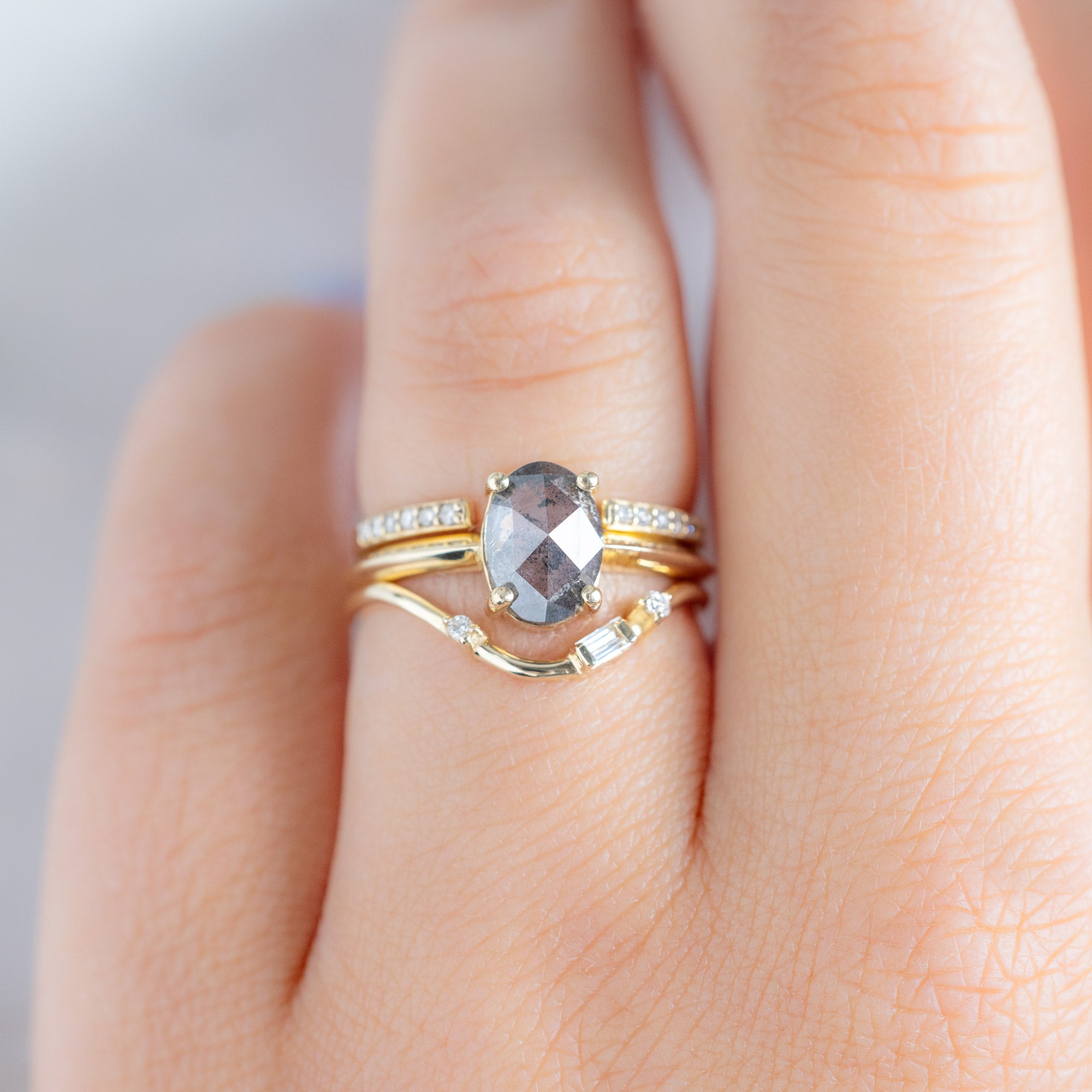 Asymmetrical Baguette Diamond Arc Stacking Band in 14K Yellow Gold stacked with oval shaped diamond engagement ring on model