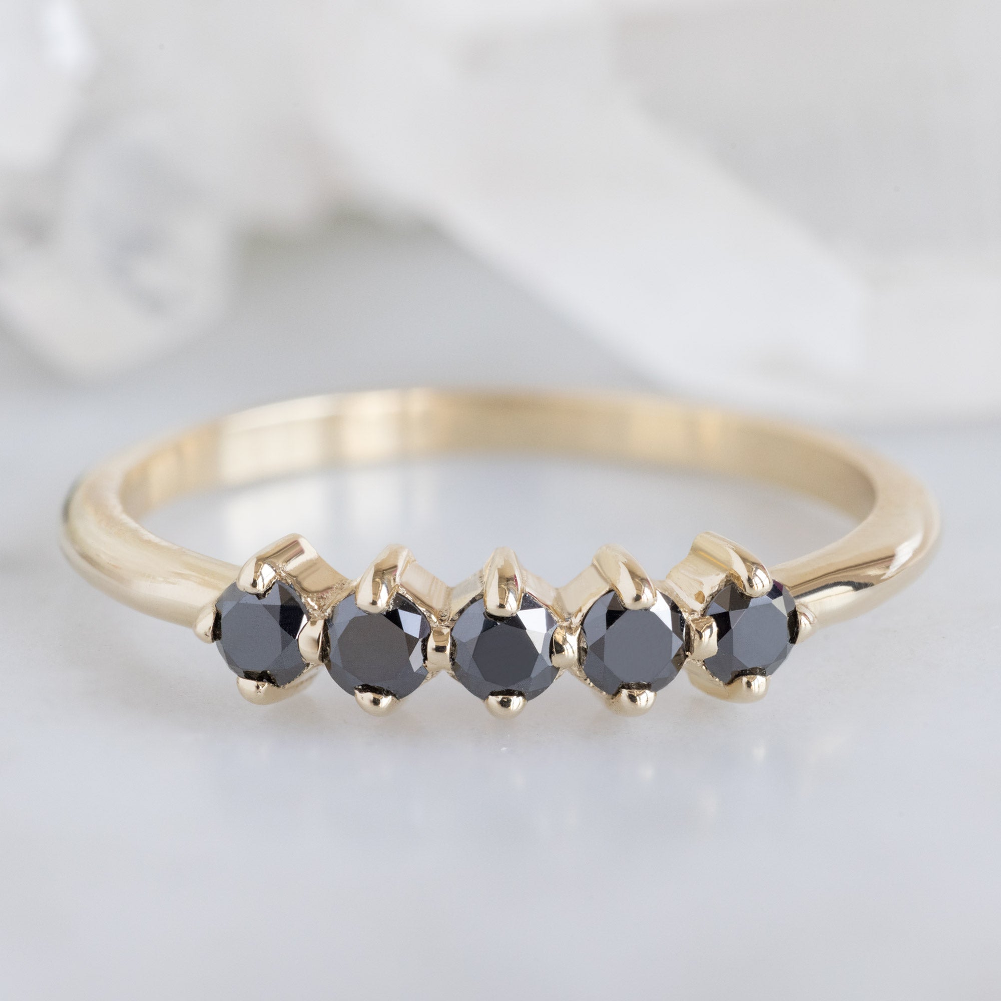 The Sequent Black Diamond Wedding Band in 14K Yellow Gold on White Marble