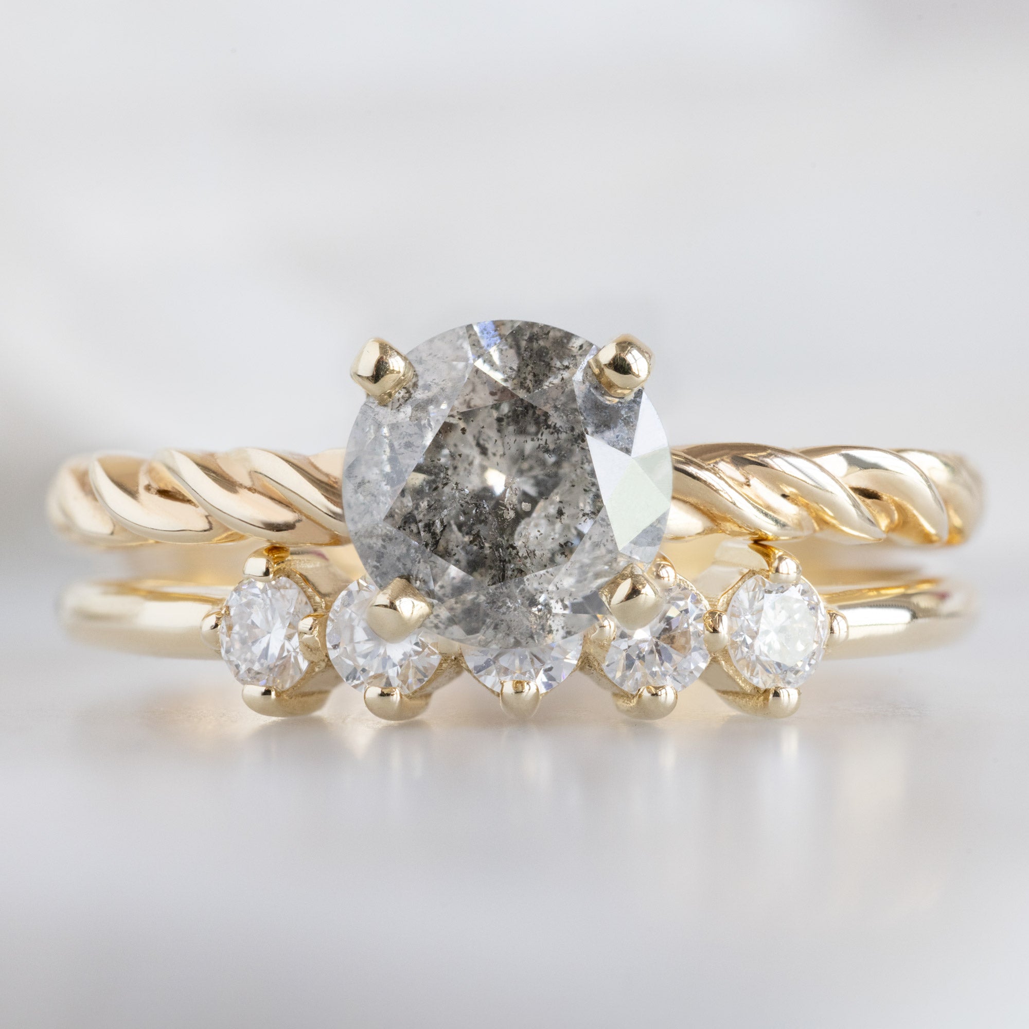 The Sequent White Diamond Wedding Band in 14K Yellow Gold Stacked with Round Salt and Pepper Diamond Engagement Ring on White Marble