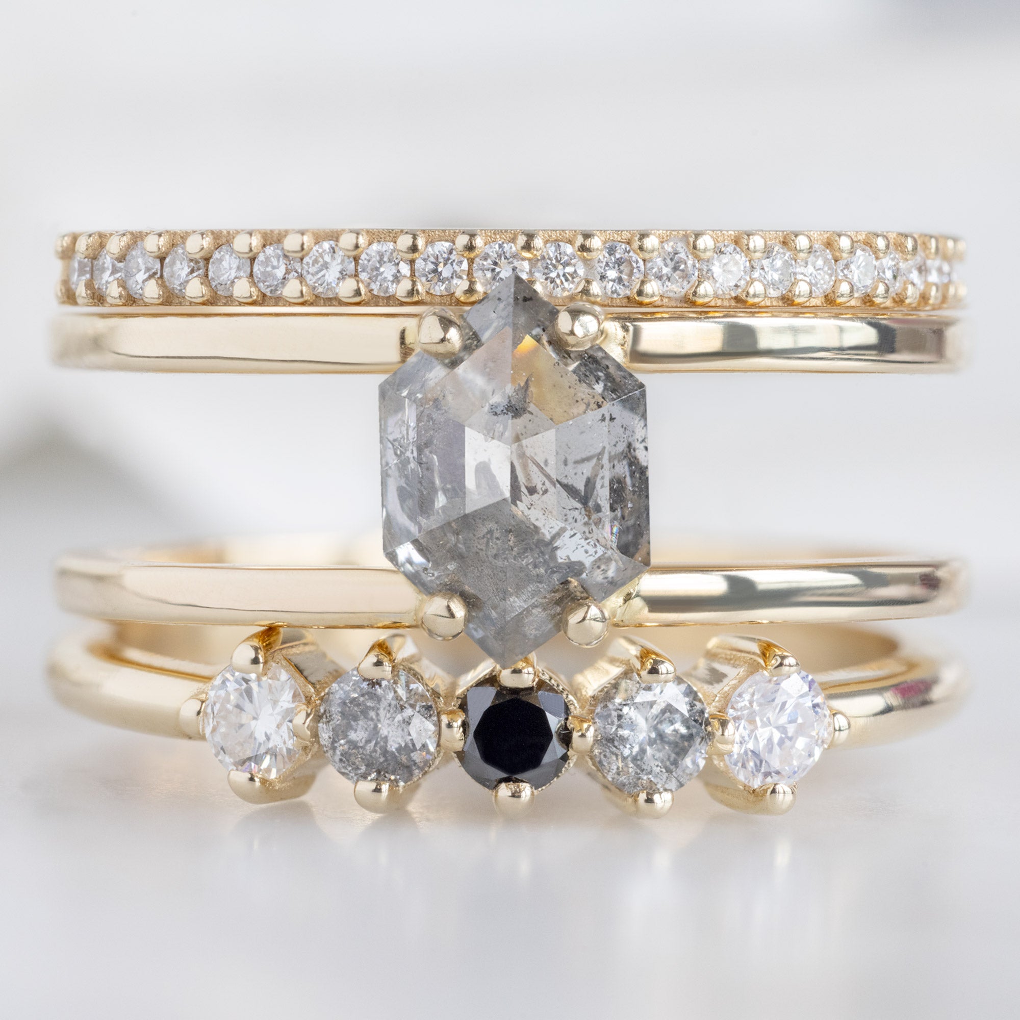 The Sequent Ombré Diamond Wedding Band in 14K Yellow Gold Stacked with Double Band Salt and Pepper Diamond Engagement Ring on White Marble