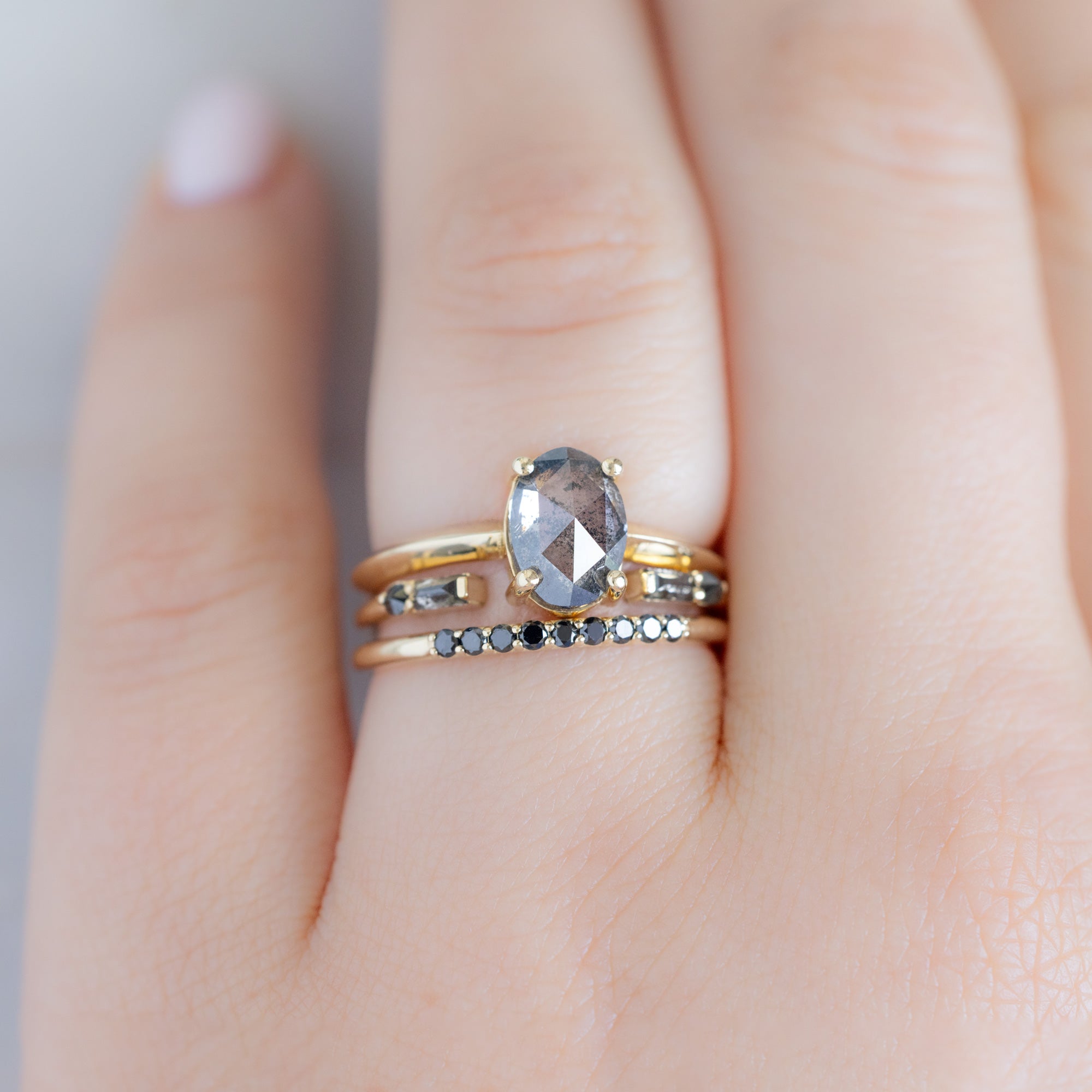 The Luxe Black Diamond Pavé Wedding Band in 14K Yellow Gold Stacked with Oval Salt and Pepper Diamond Engagement Ring on Marble