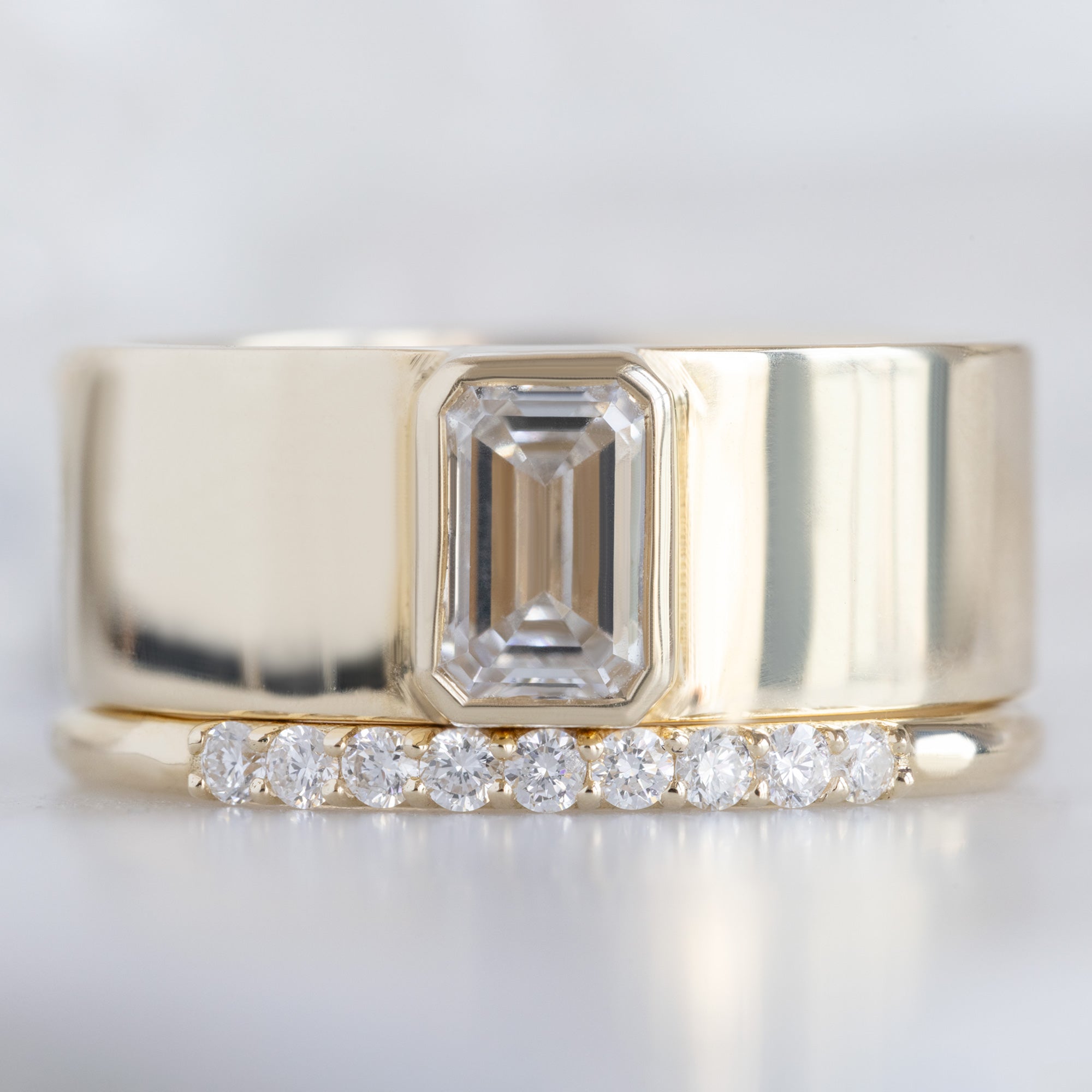 The Luxe White Diamond Pavé Wedding Band in 14k Yellow Gold Stacked with the Cigar Band with White Diamond on White Marble
