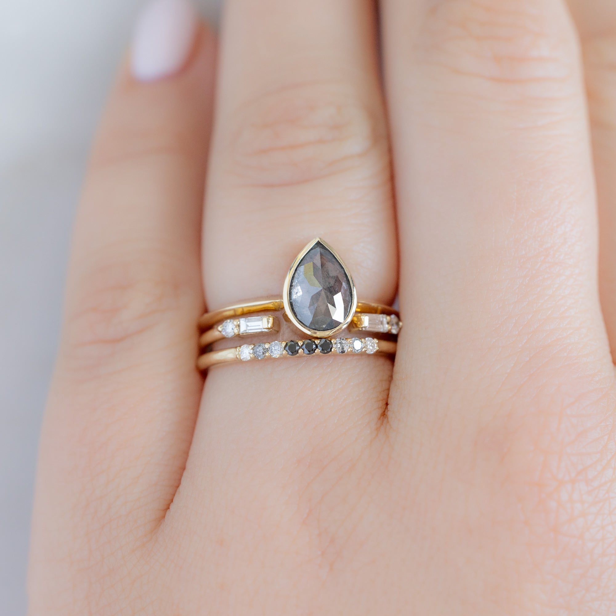 The Luxe Ombré Diamond Pavé Wedding Band in 14K Yellow Gold Stacked with Black Diamond Pear Engagement Ring on Model