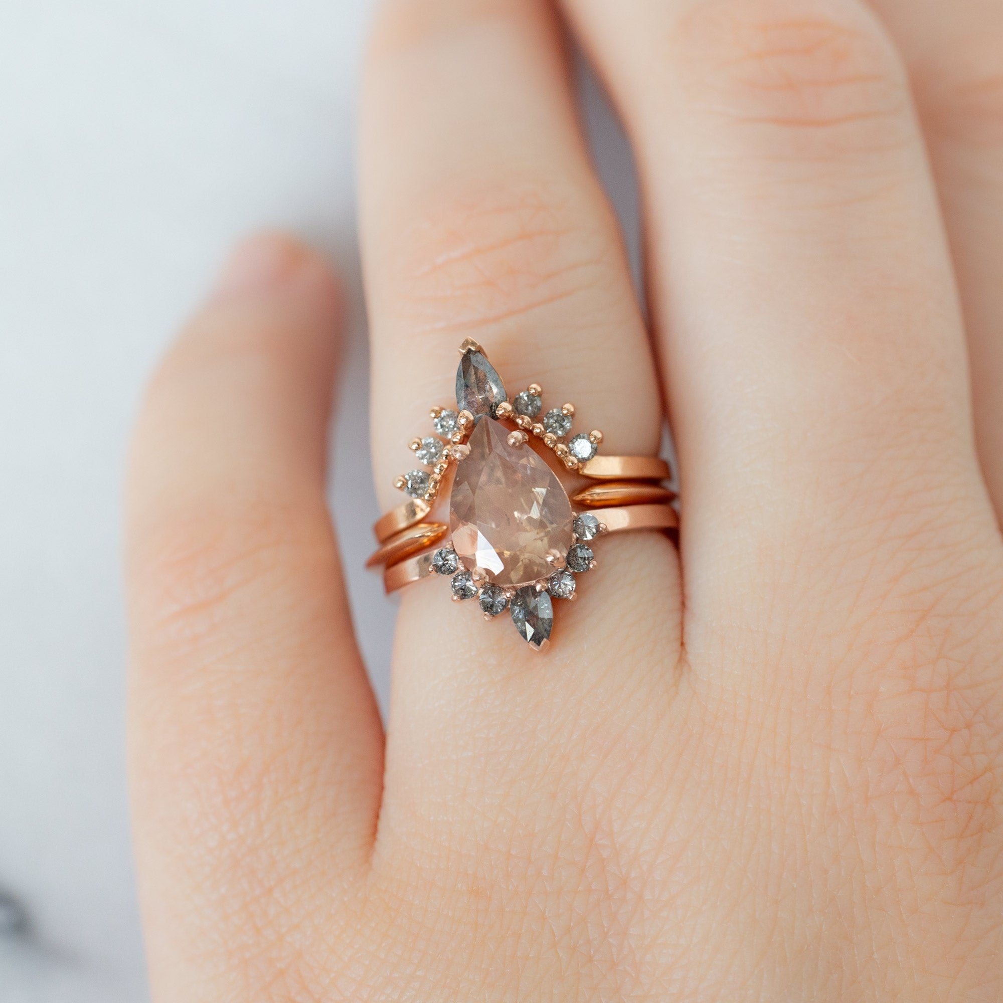 Salt and Pepper Diamond Sunburst Stacking Band in 14K Rose Gold Stacked with Sunstone Pear Engagement Ring on Model